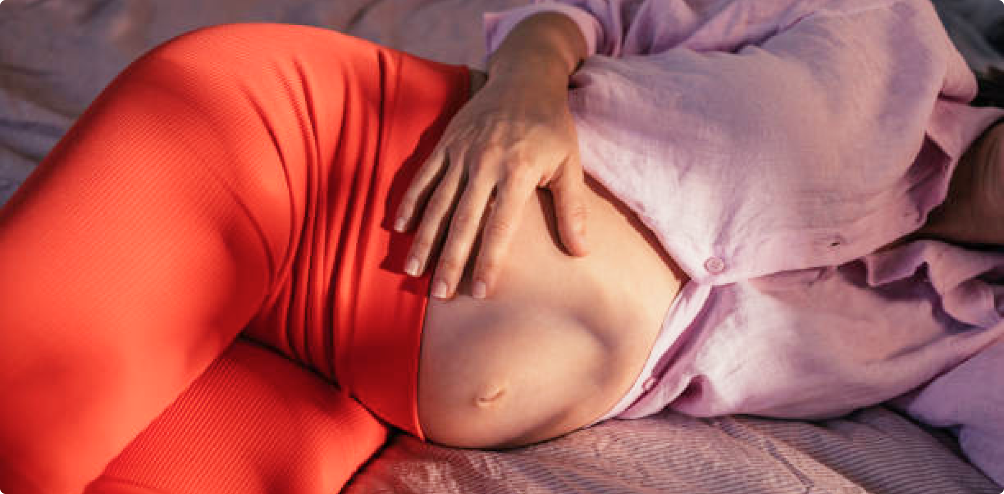 Schwangerschaft Image Banner (Title/Caption) Pregnant woman lying in bed exposing and holding her belly (Alternate Tet)