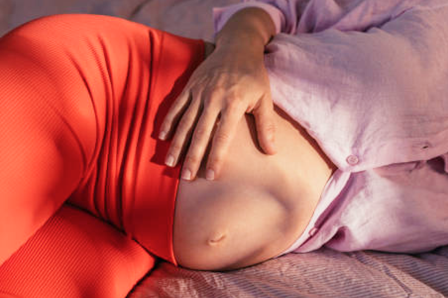 Schwangerschaft Image Banner (Title/Caption) Pregnant woman lying in bed exposing and holding her belly (Alternate Tet)