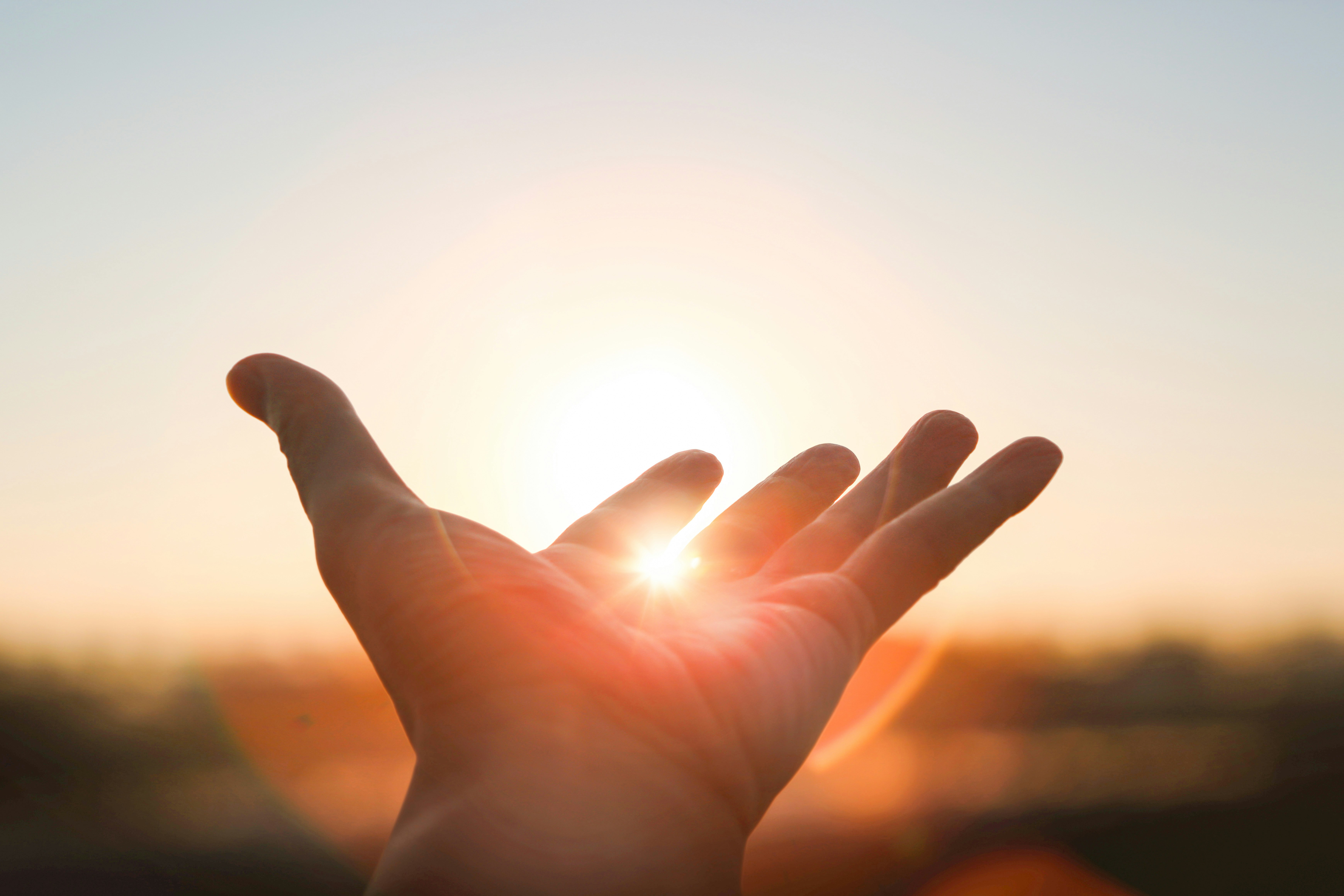 hand_mit_sonnenstrahlen_im_hintergrund hand_mit_sonnenstrahlen_im_hintergrund
