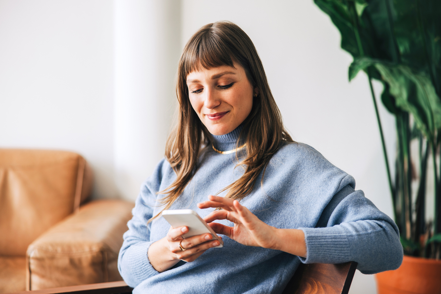 Frau am Handy im Wohnzimmer