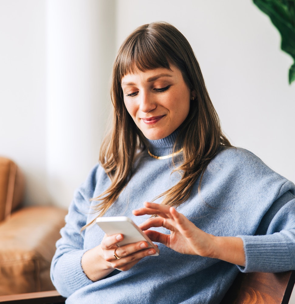Frau am Handy im Wohnzimmer Frau am Handy im Wohnzimmer
