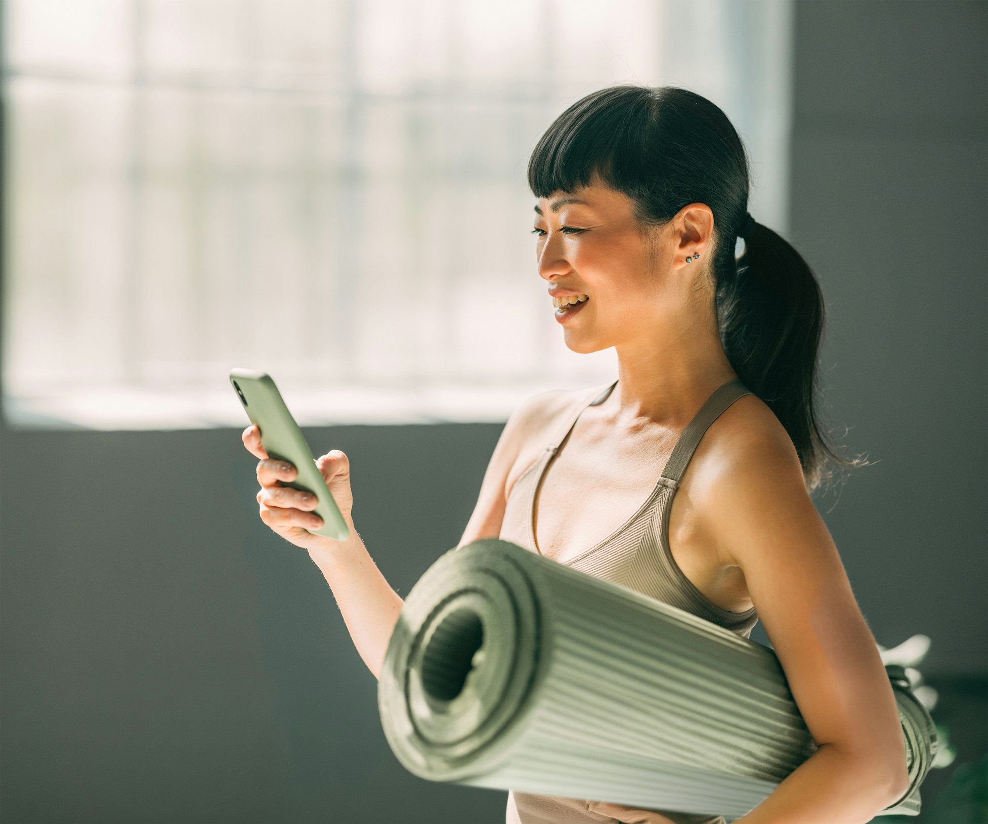 Frau mit Jogamatte am Handy
