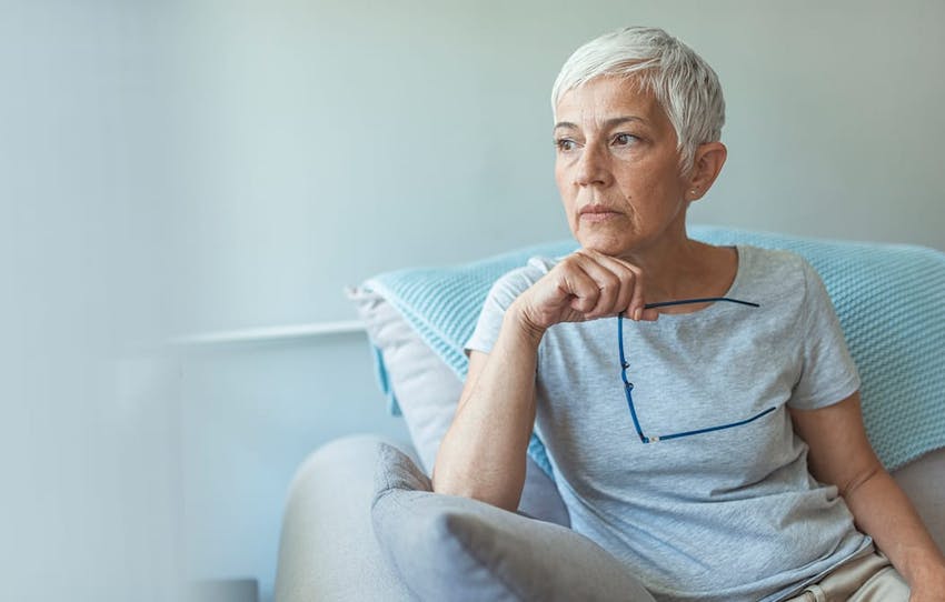 older woman holding her glasses