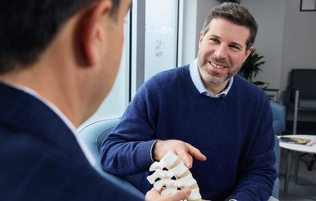 patient pointing to a plastic spine