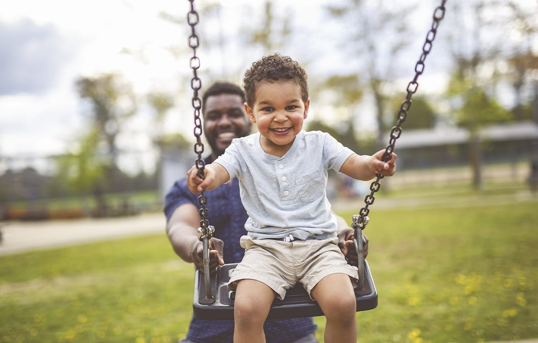 man pushing a child on a swing