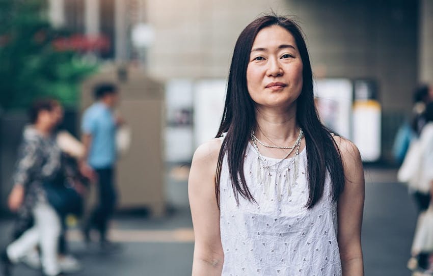 woman standing outside with kids walking behind her