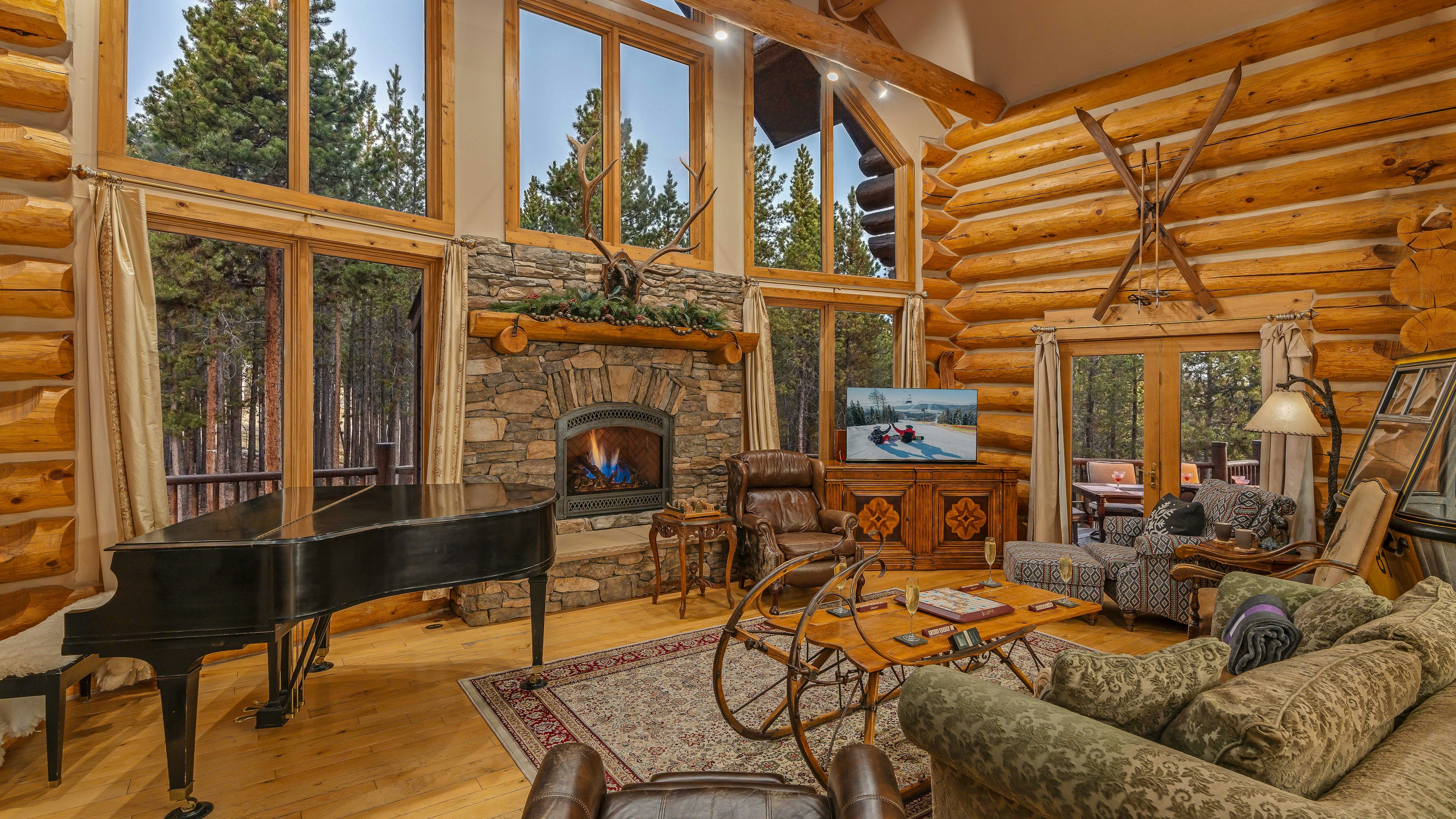 Great room with fireplace, TV, vintage gondola car, and deck access