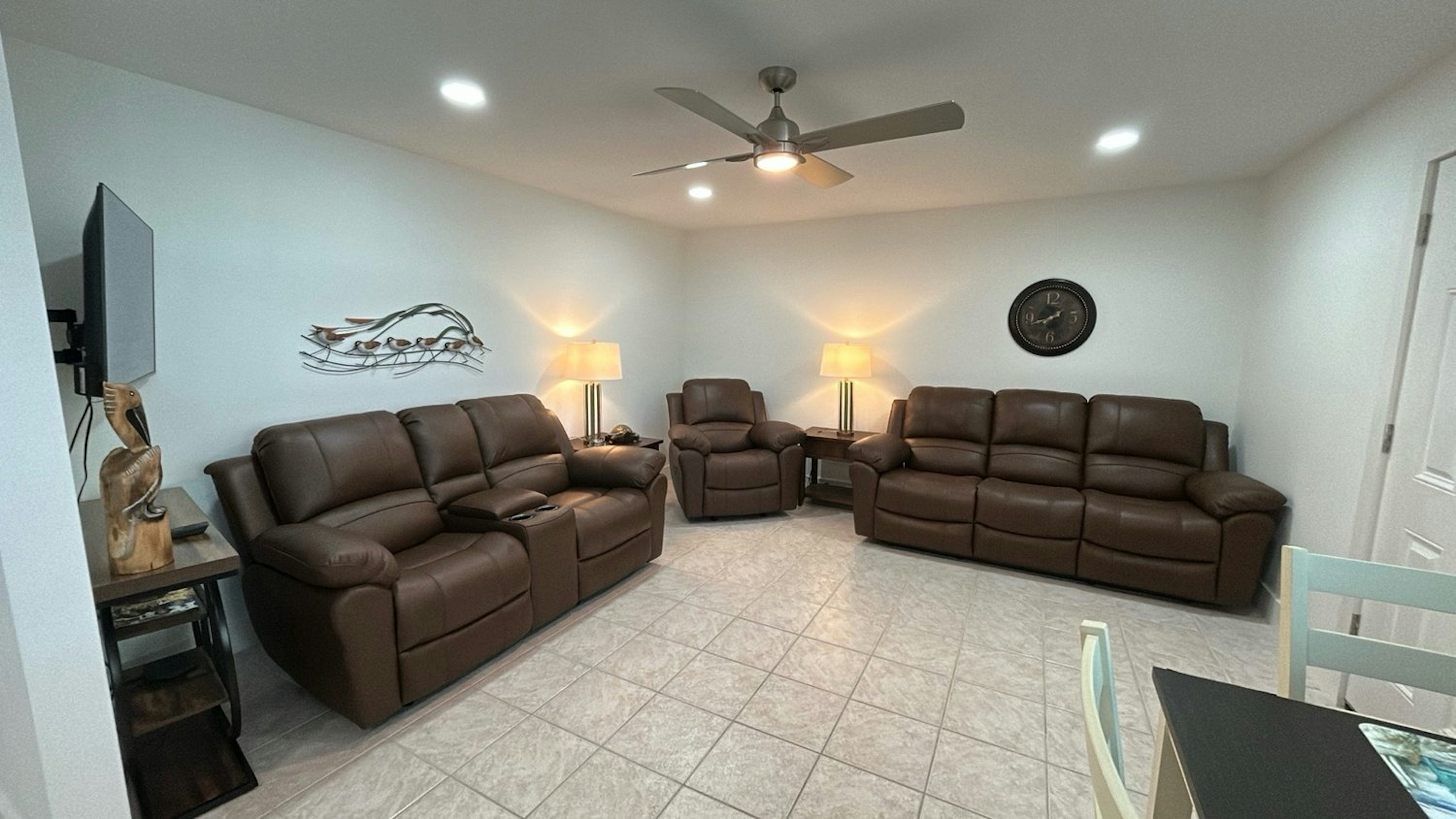 Sink into luxurious leather recliners in your spacious living area, where warm lighting and a ceiling fan create the perfect atmosphere for movie nights.