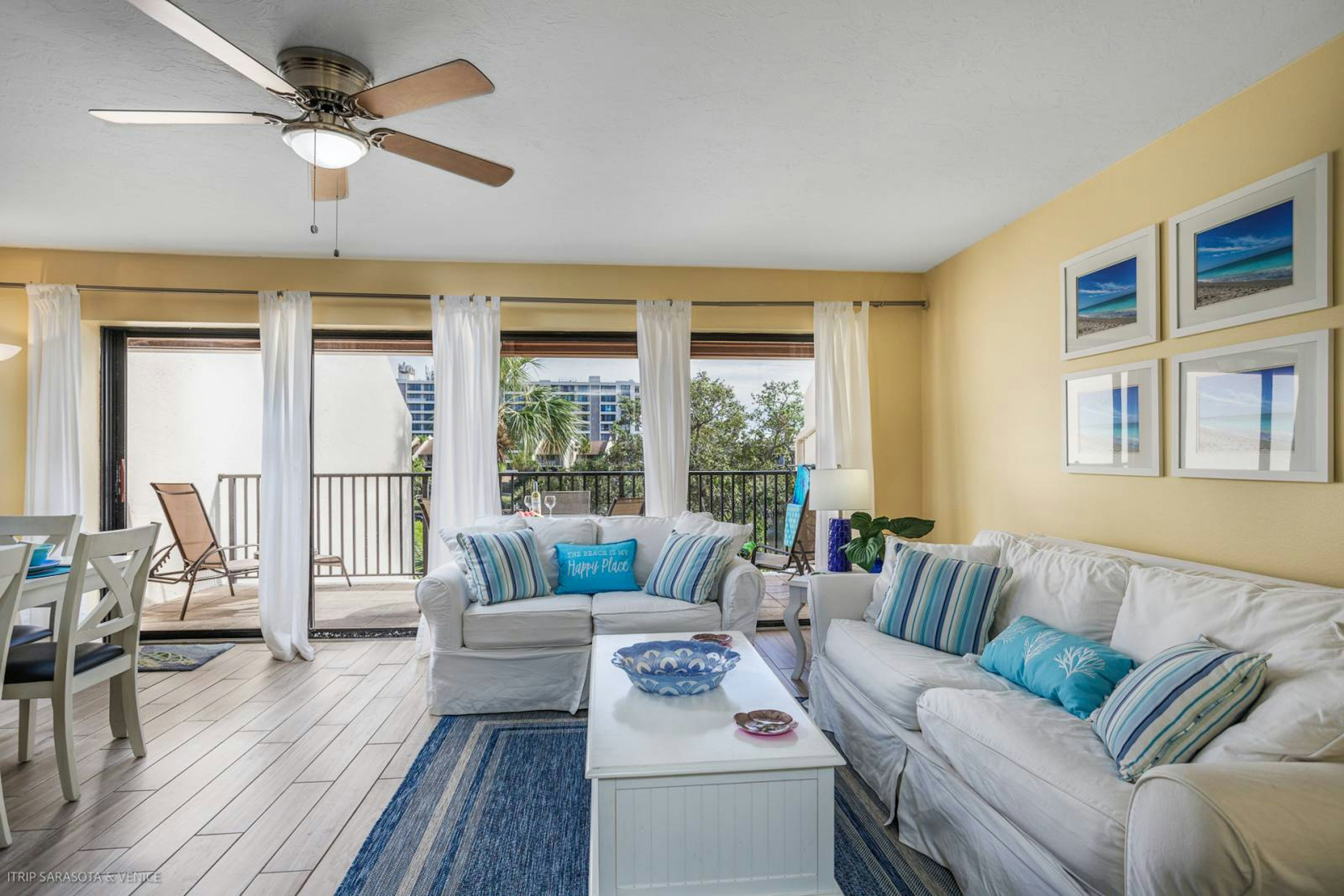 Relax in your bright living room with coastal decor, ceiling fan, and balcony access to enjoy comfortable indoor-outdoor living.
