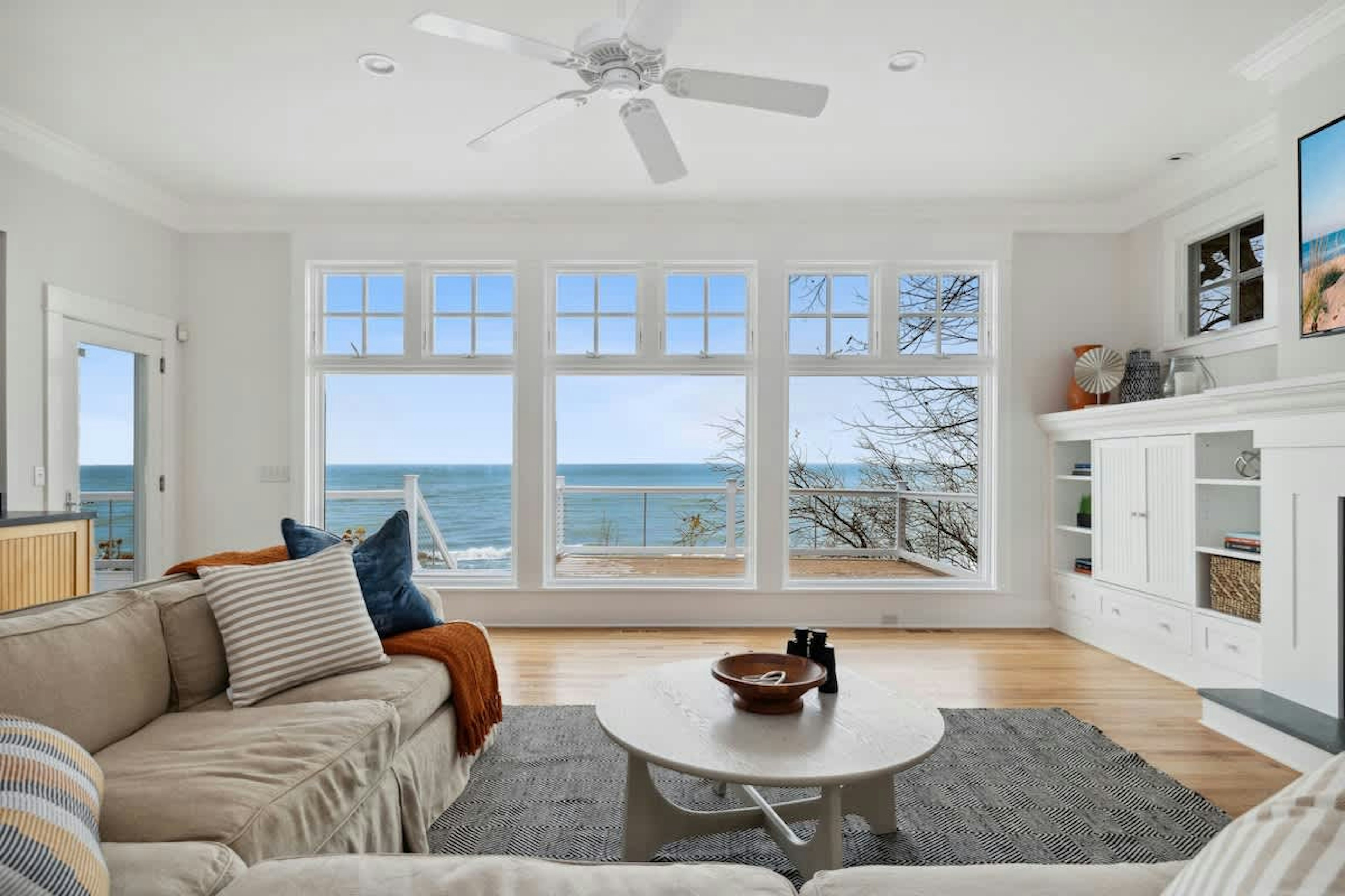Sink into plush coastal comfort while ocean waves dance beyond your panoramic windows in this bright, airy living space.