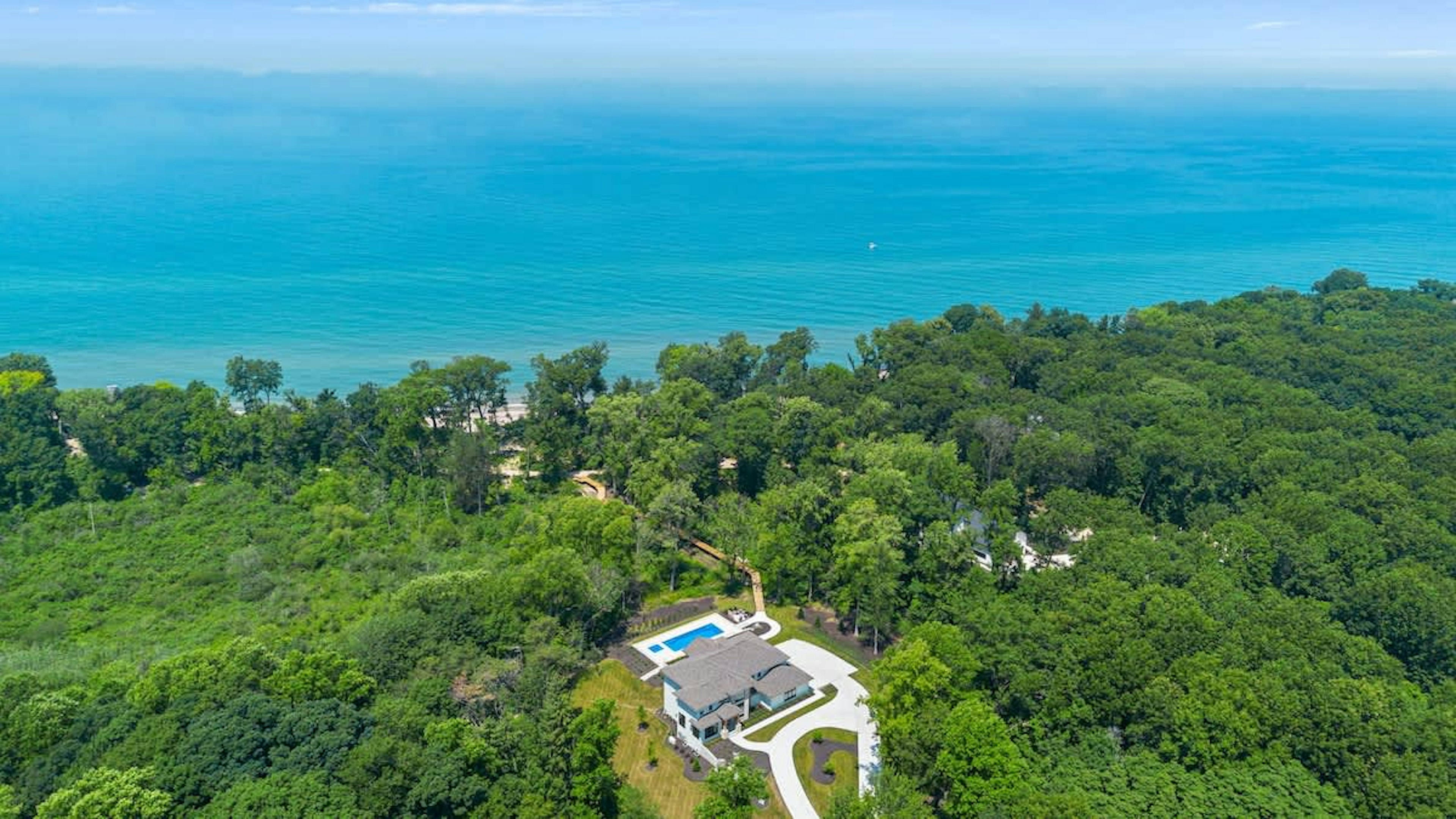 This aerial view captures the beauty of a house nestled amidst lush trees and serene waters.