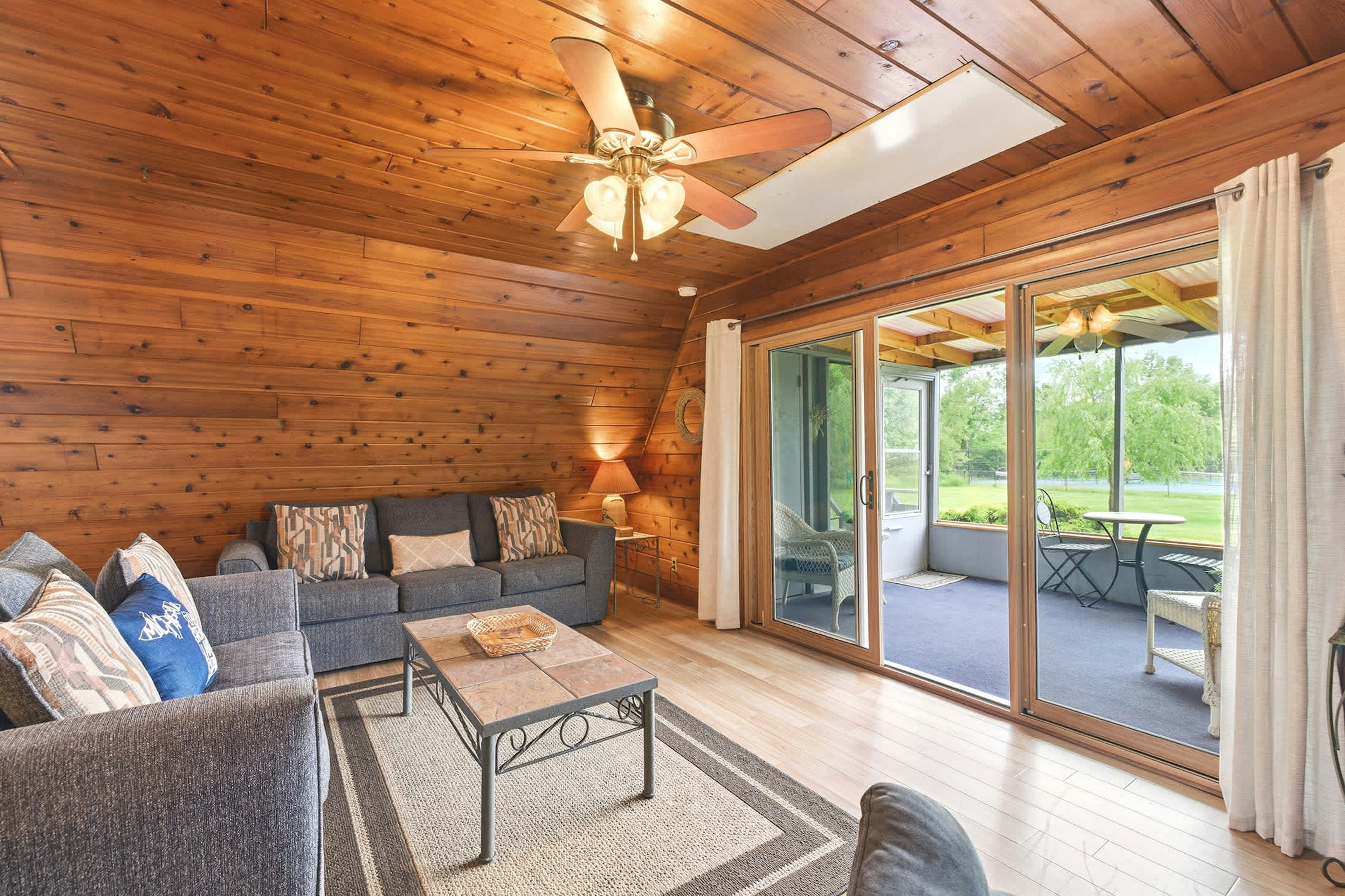 Living area opens to a screened porch overlooking green resort space.