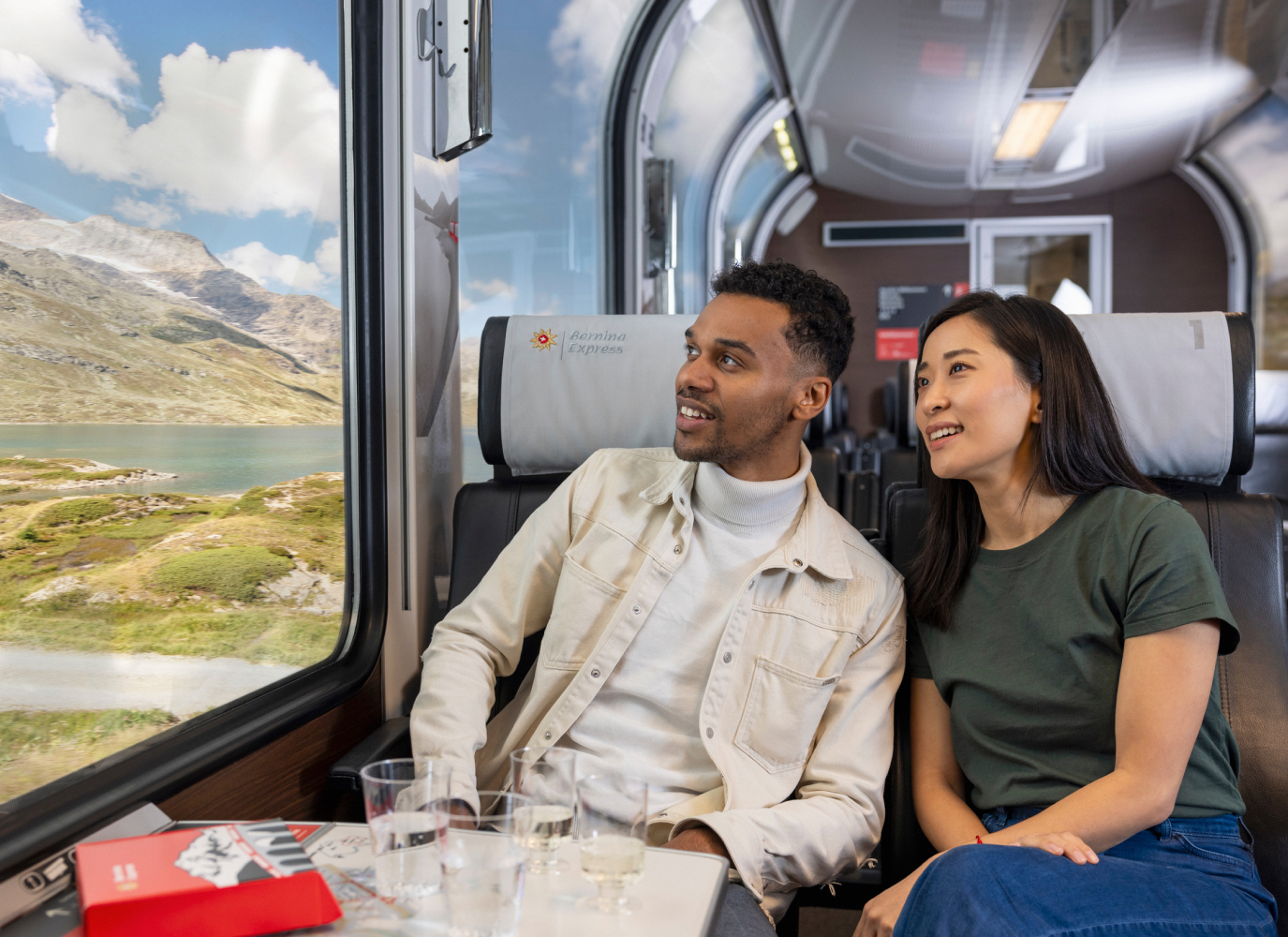Tourist couple sitting in a panorama train looking out of the window.
