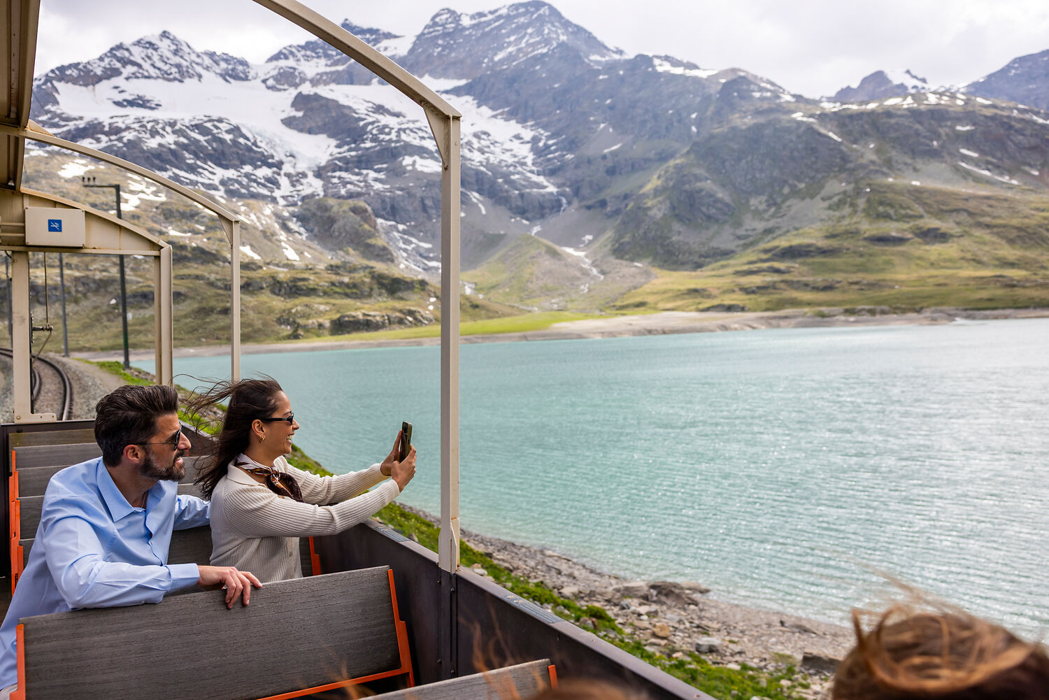 NICOLA PITARO Couple sitting outside the Bernina Express Pullman Class taking pictures of the beautiful landscape