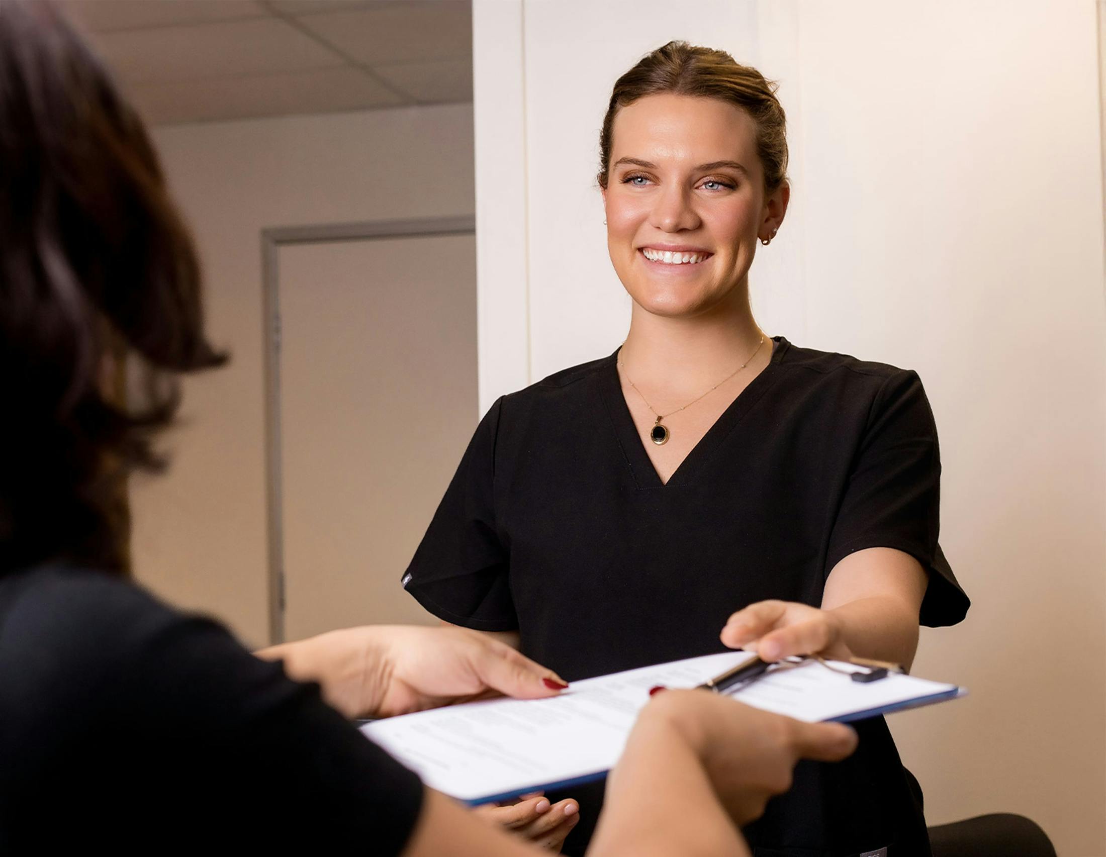 Woman smiling and being handed a clipboard