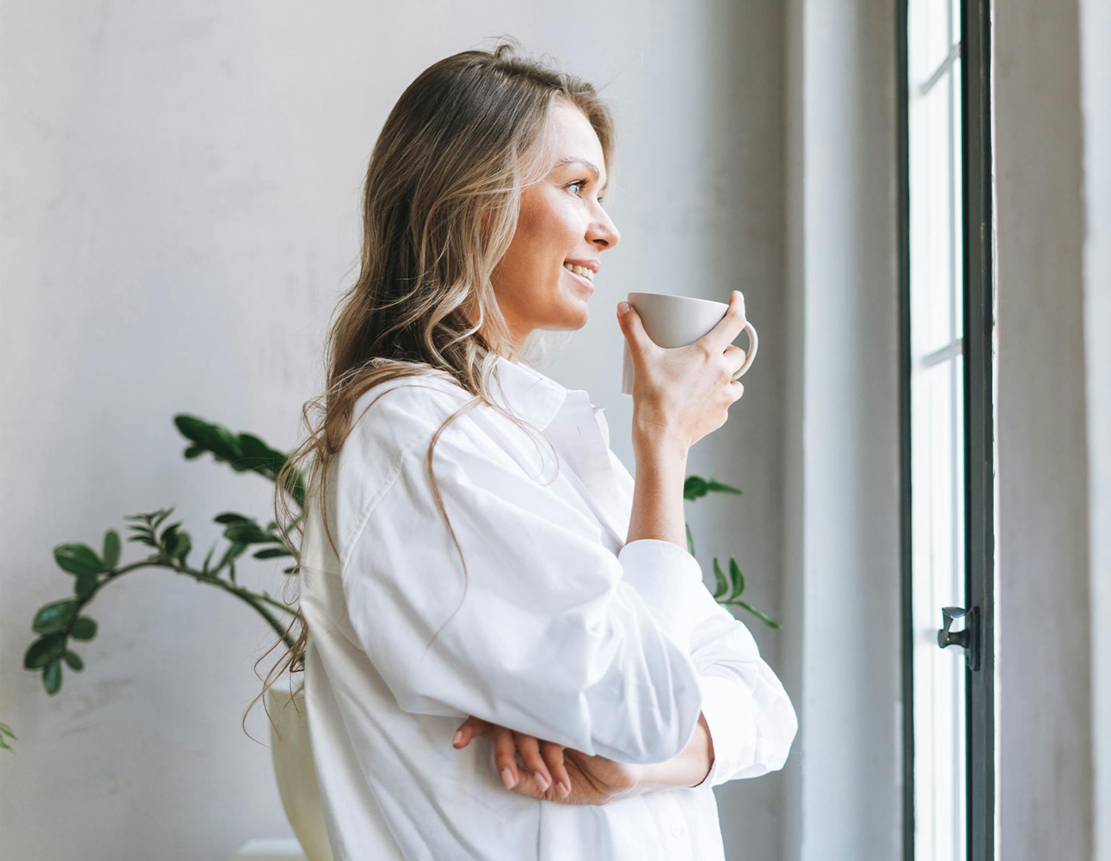 Woman with coffee looking out the window