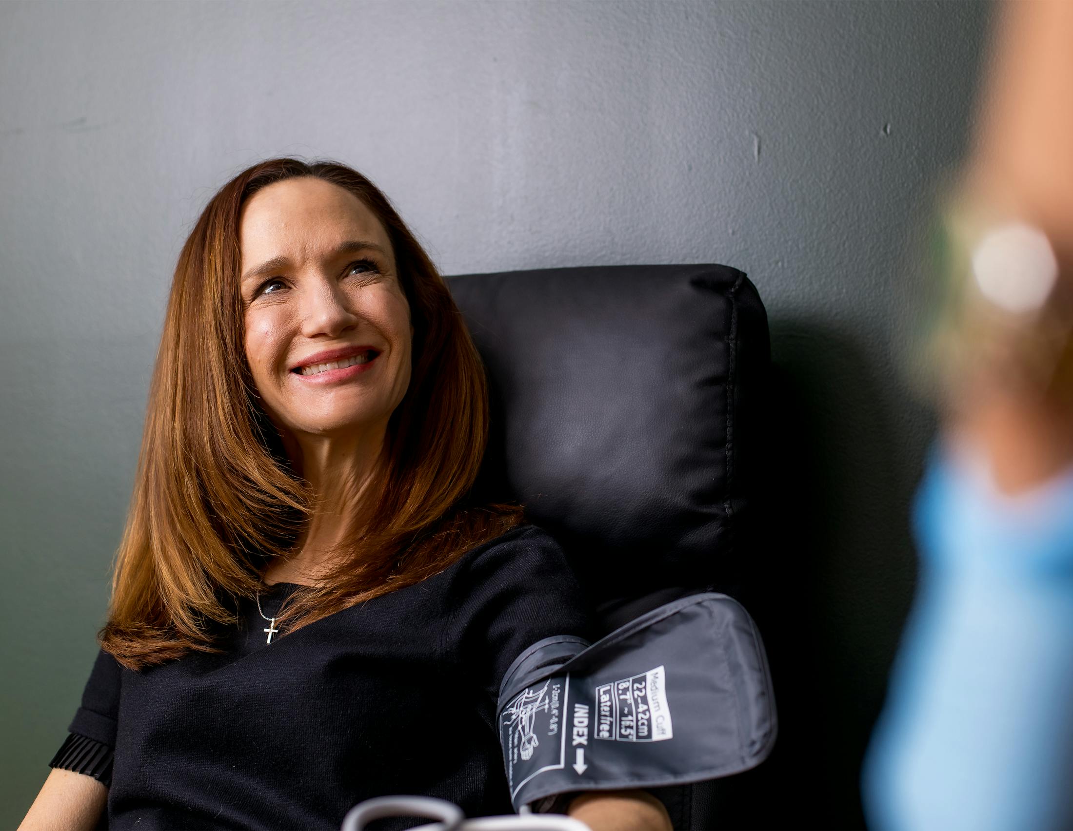 Woman sitting on a couch filling out paperwork smiling