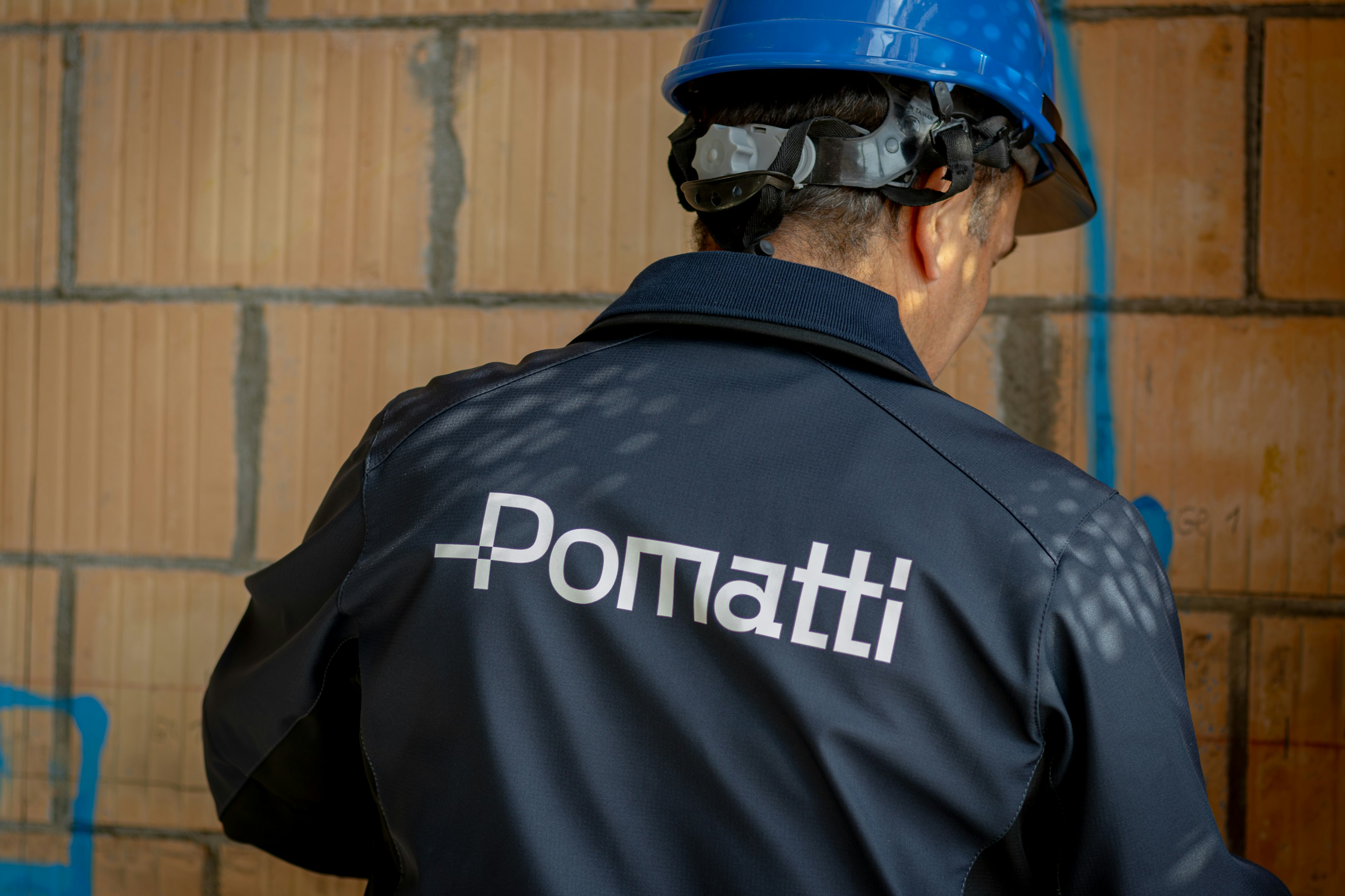 Pomatti Mitarbeiter auf Baustelle mit Pomatti Jacke und Helm