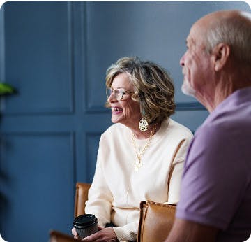 Woman and man sitting in chairs in front of a blue wall