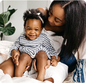 Baby in a striped shirt sitting in her moms lap