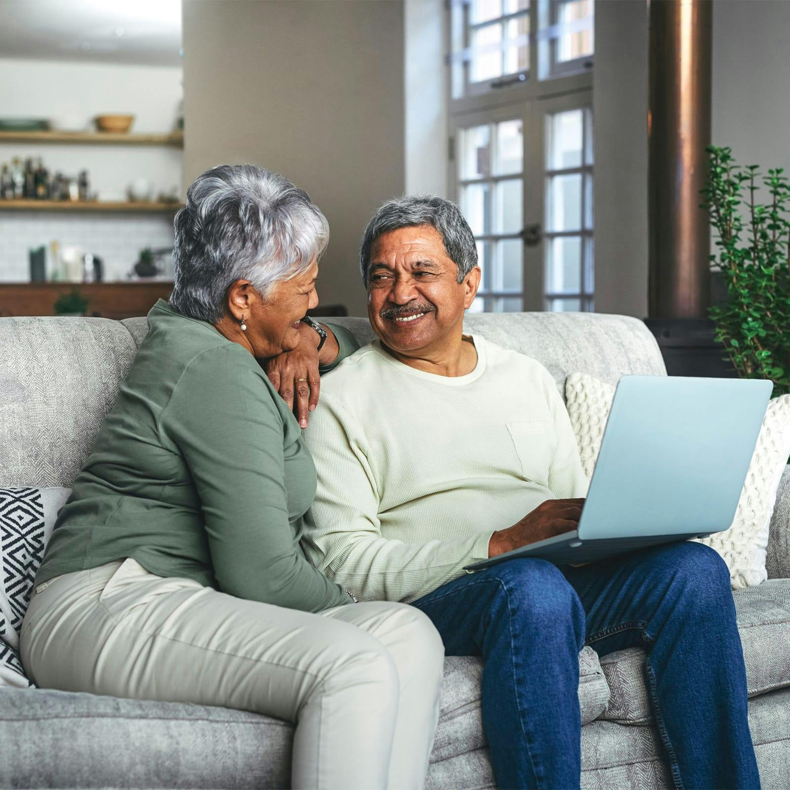 old couple sitting on a couch with a laptop