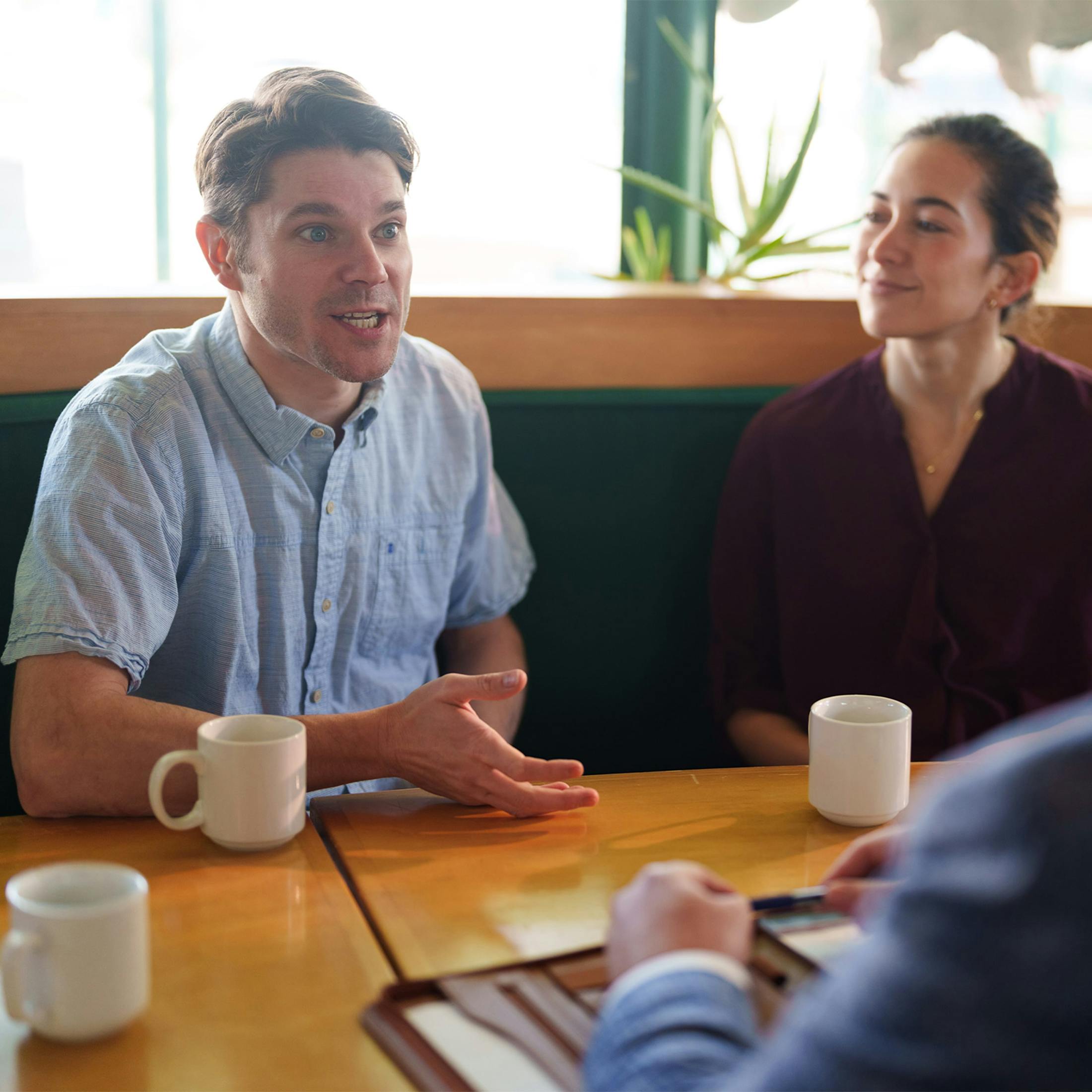 man and woman looking at a phone while sitting with coffee