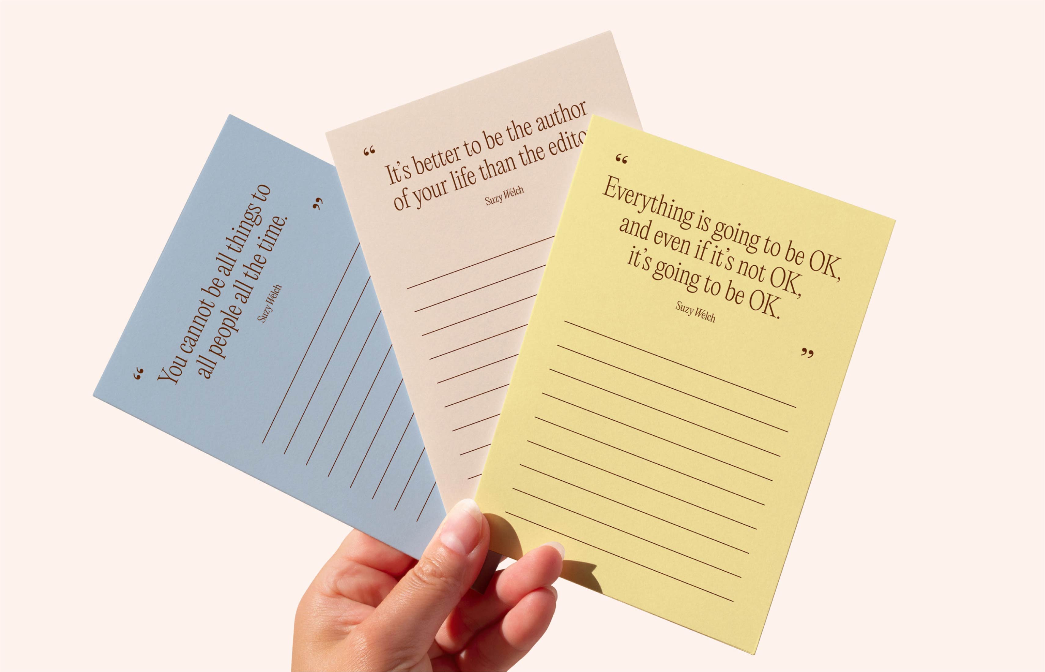 Suzy Welch worksheets in blue, pink, and yellow held in hand.