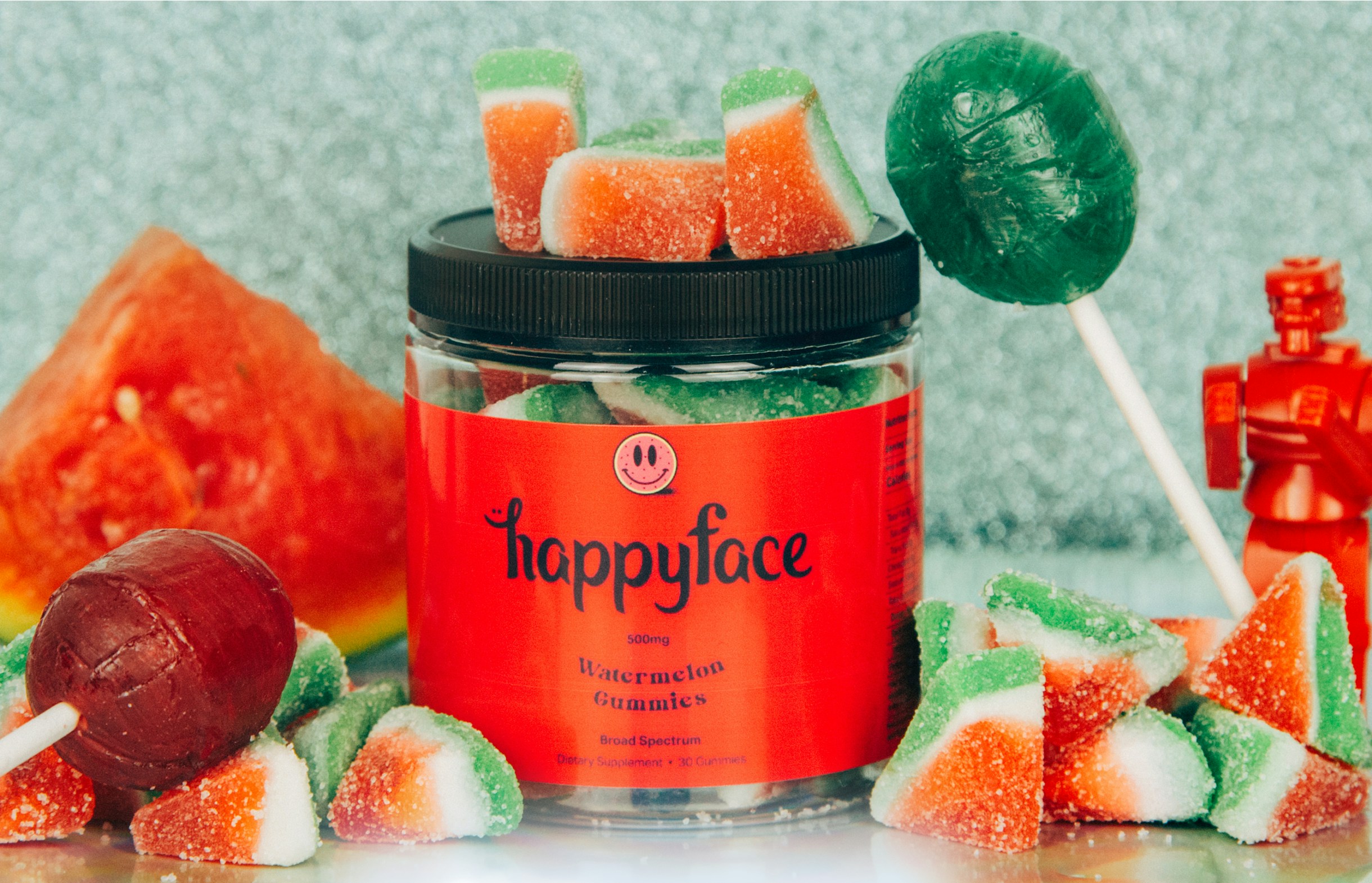 Close-up of Happy Face supplement jar with fruit ingredients and playful red packaging, showcasing bold consumer brand design.