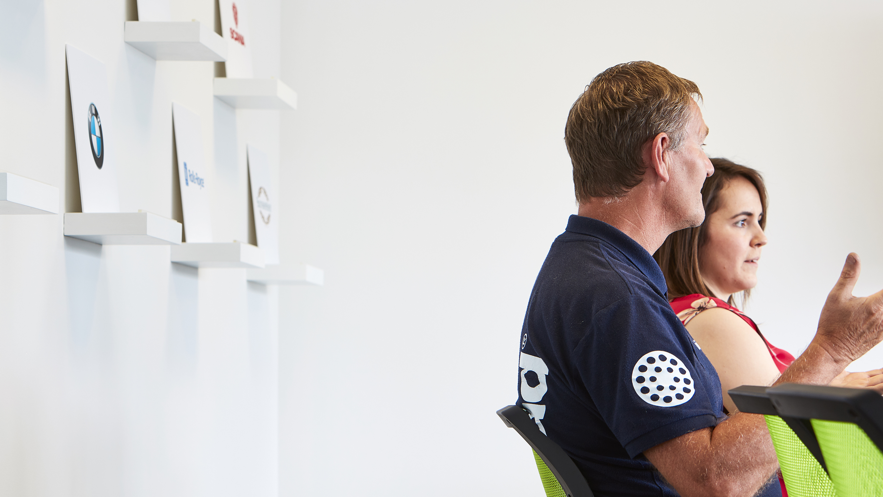 bigHead engineers and clients in meeting room with stand-out client logos like BMW displayed on shelves in background on clean white wall