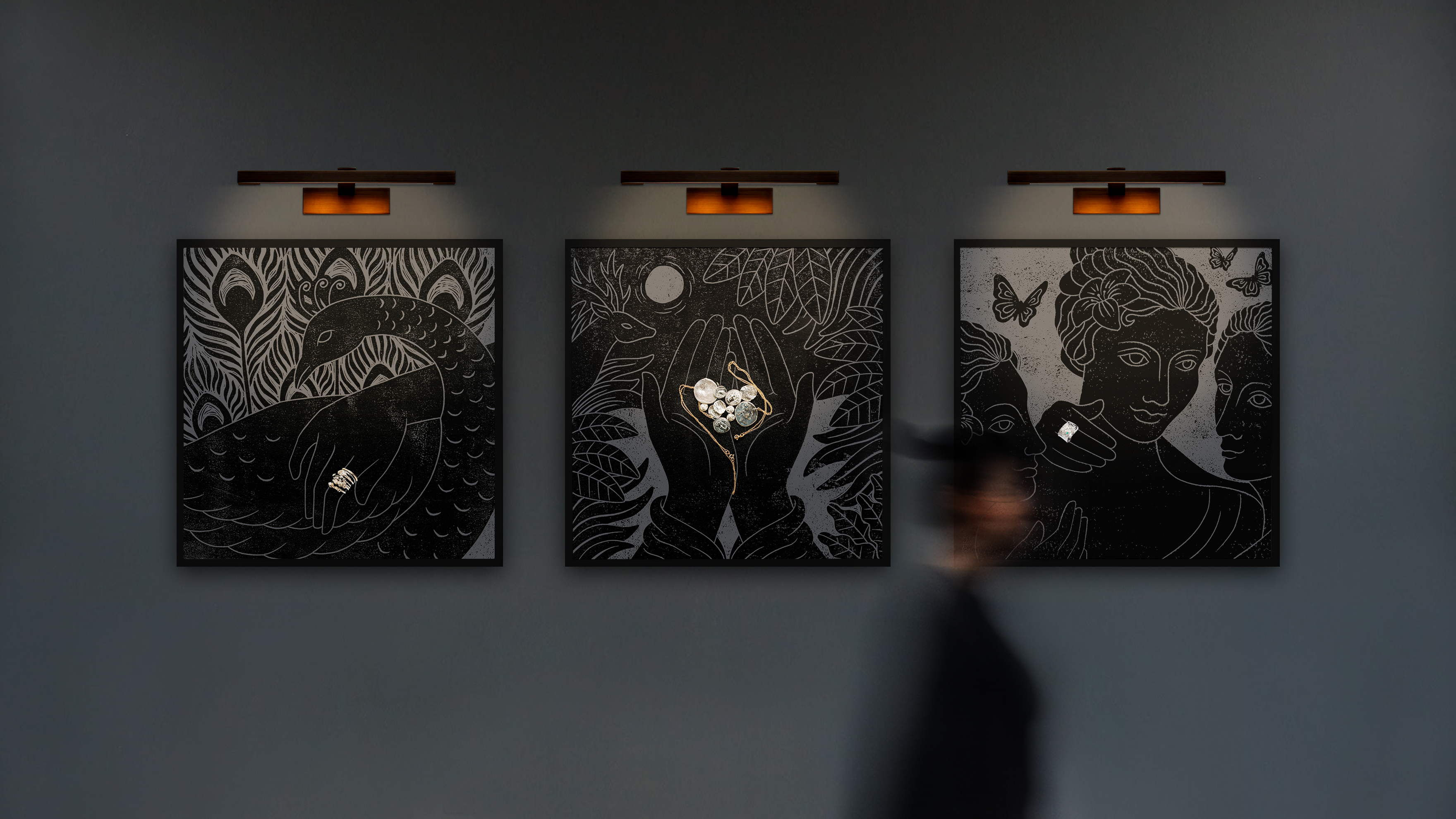 Grey wall in low-light jewellery boutique with three framed Greek goddess illustrations in grey and black, each featuring handcrafted jewellery