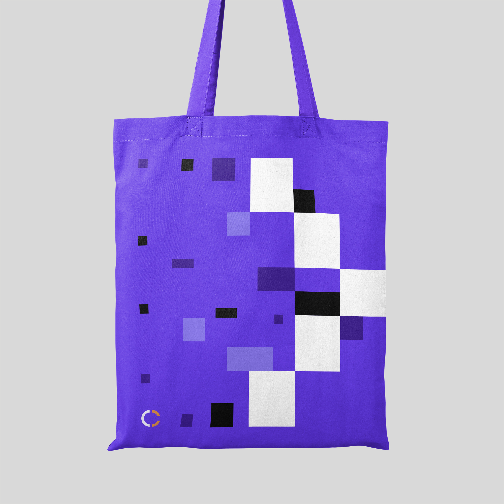 Purple tote bag with abstract arrow-style pixel design and Conjura logo, hanging against light grey studio backdrop