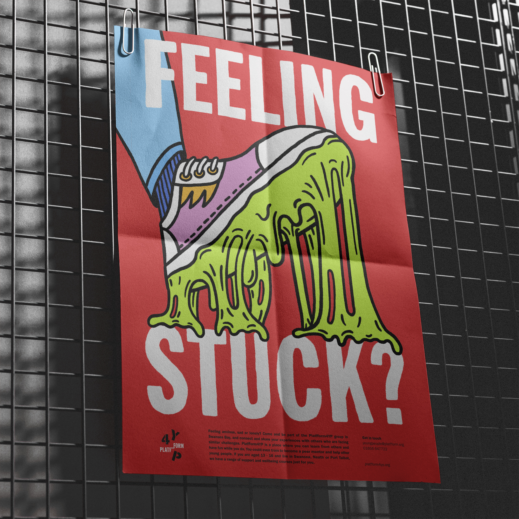 Red campaign poster on metal grid wall showing 'Feeling Stuck?' and playful illustration of shoe stepping into thick green slime