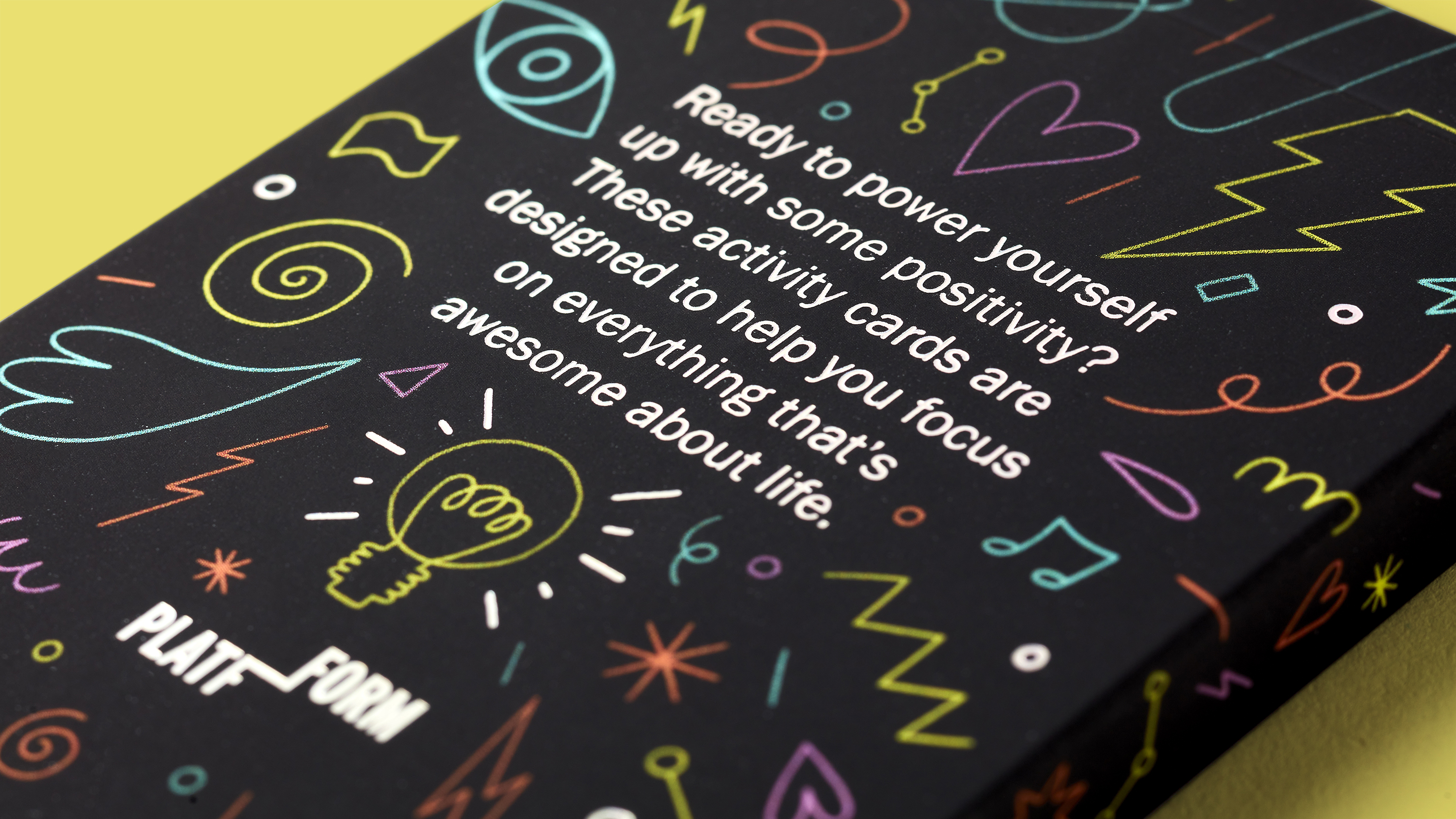 Close-up of back of Positive Power-Ups card box with colourful illustration pattern and positive life message on yellow background