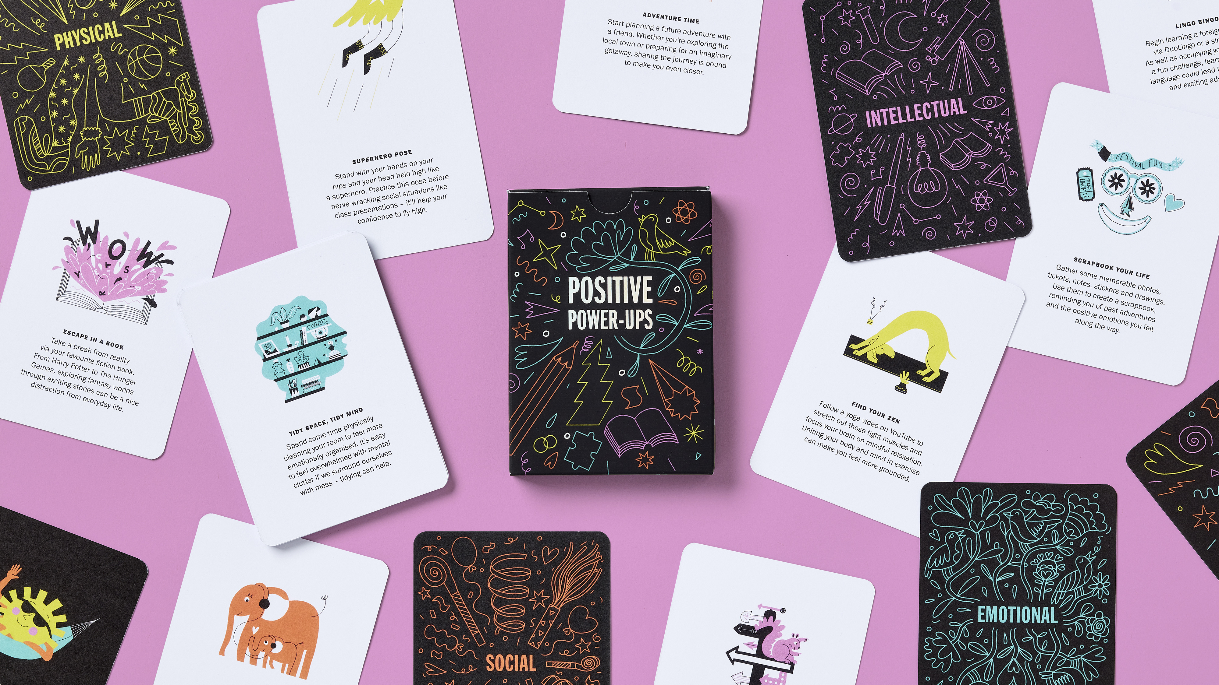 Scattered Positive Power-Up cards on pink surface with colourful illustrations and ideas to boost positivity