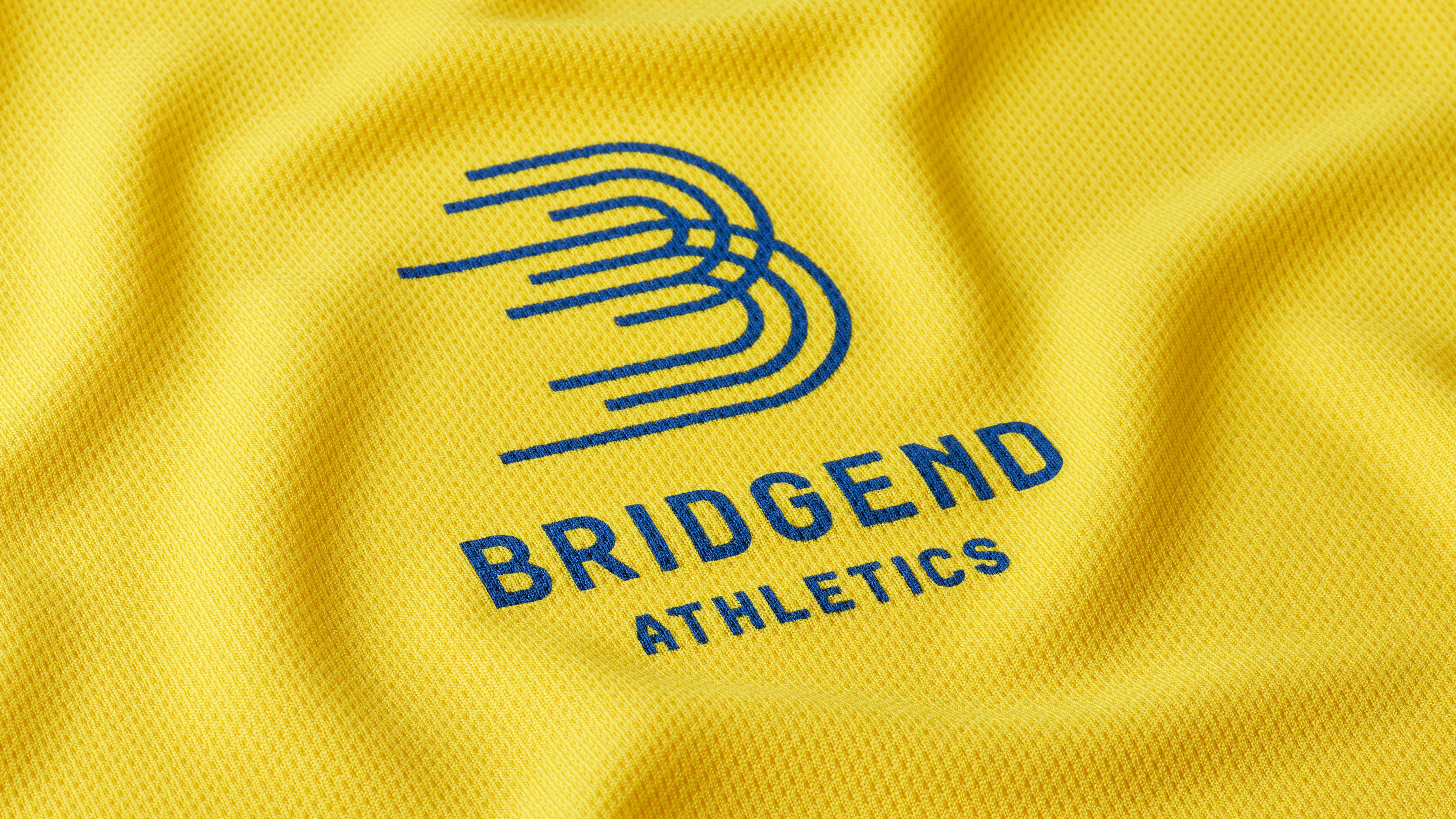 Close-up of Bridgend Athletics bright yellow jersey with blue logo on textured sports fabric