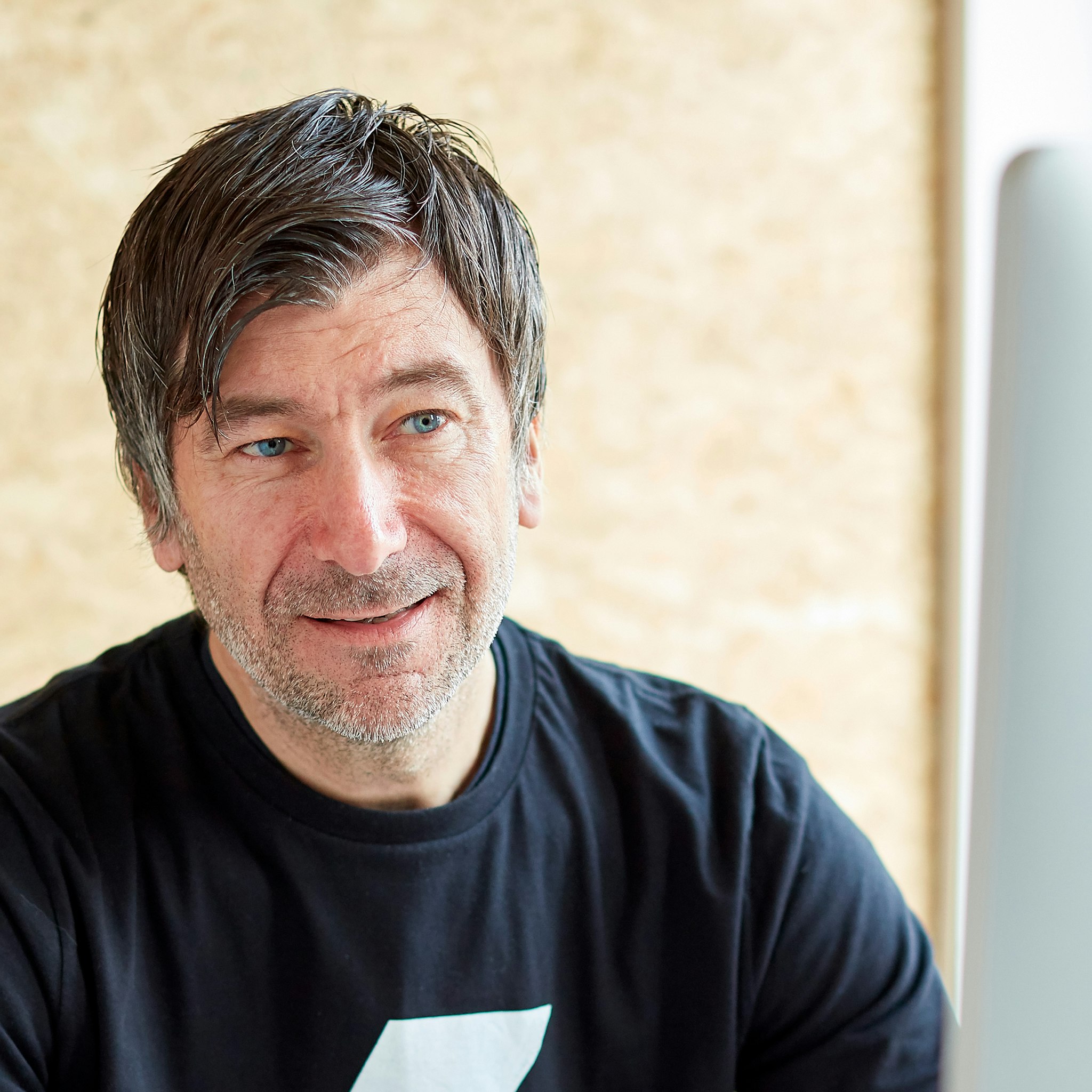 Smiling man looking past desktop computer in a modern design studio environment