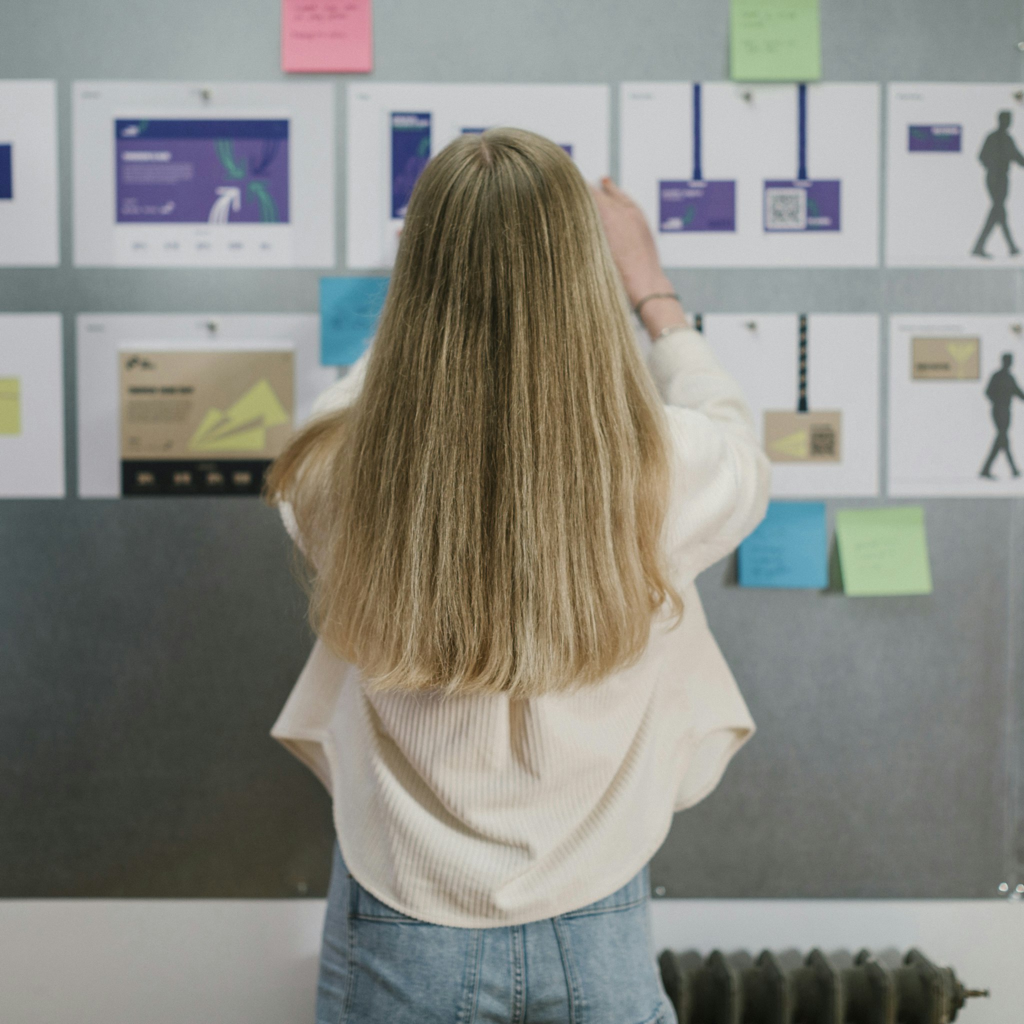 Woman brainstorming and organising design ideas on wall with creative project notes and mockups