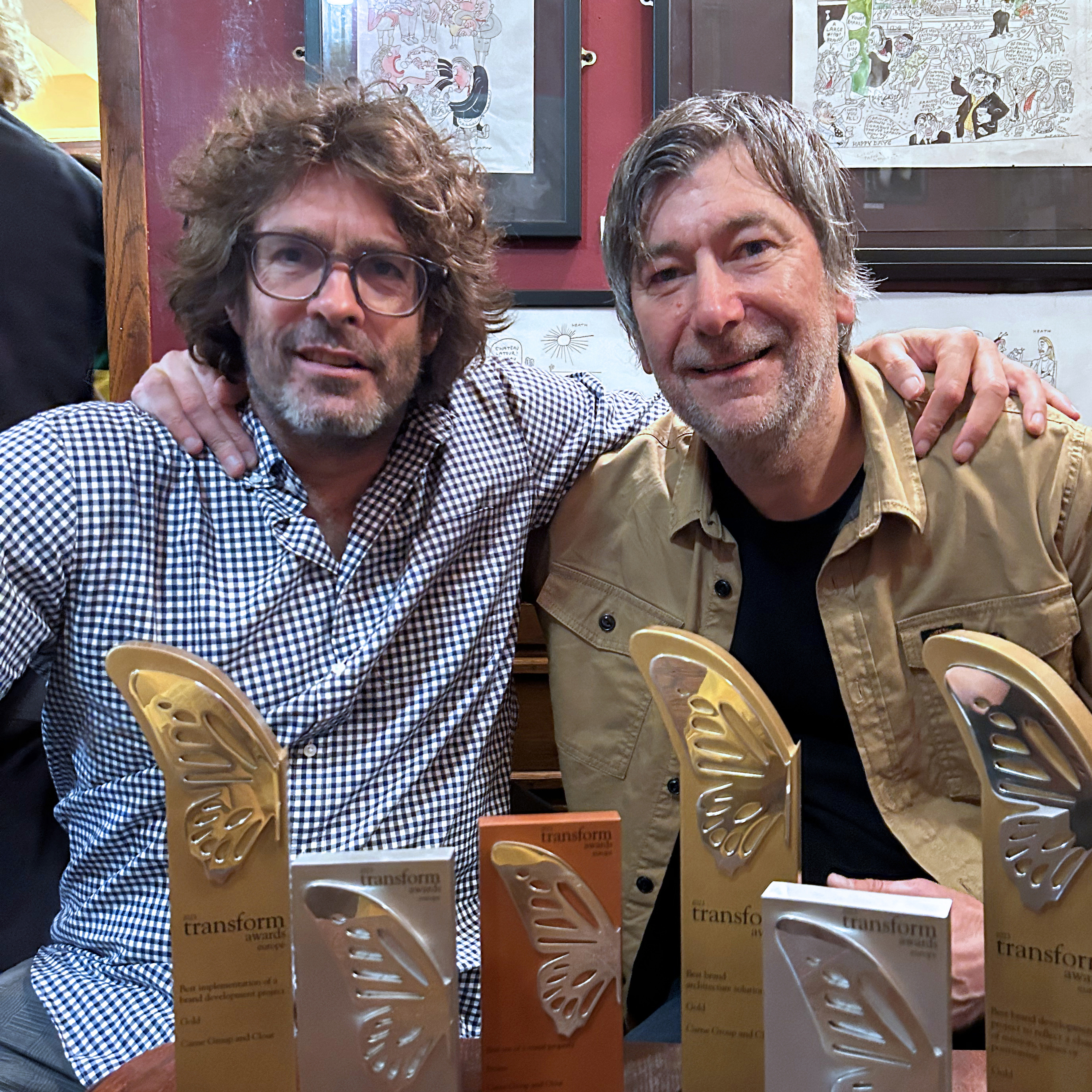 Two smiling men celebrating multiple Transform Awards for branding and design excellence