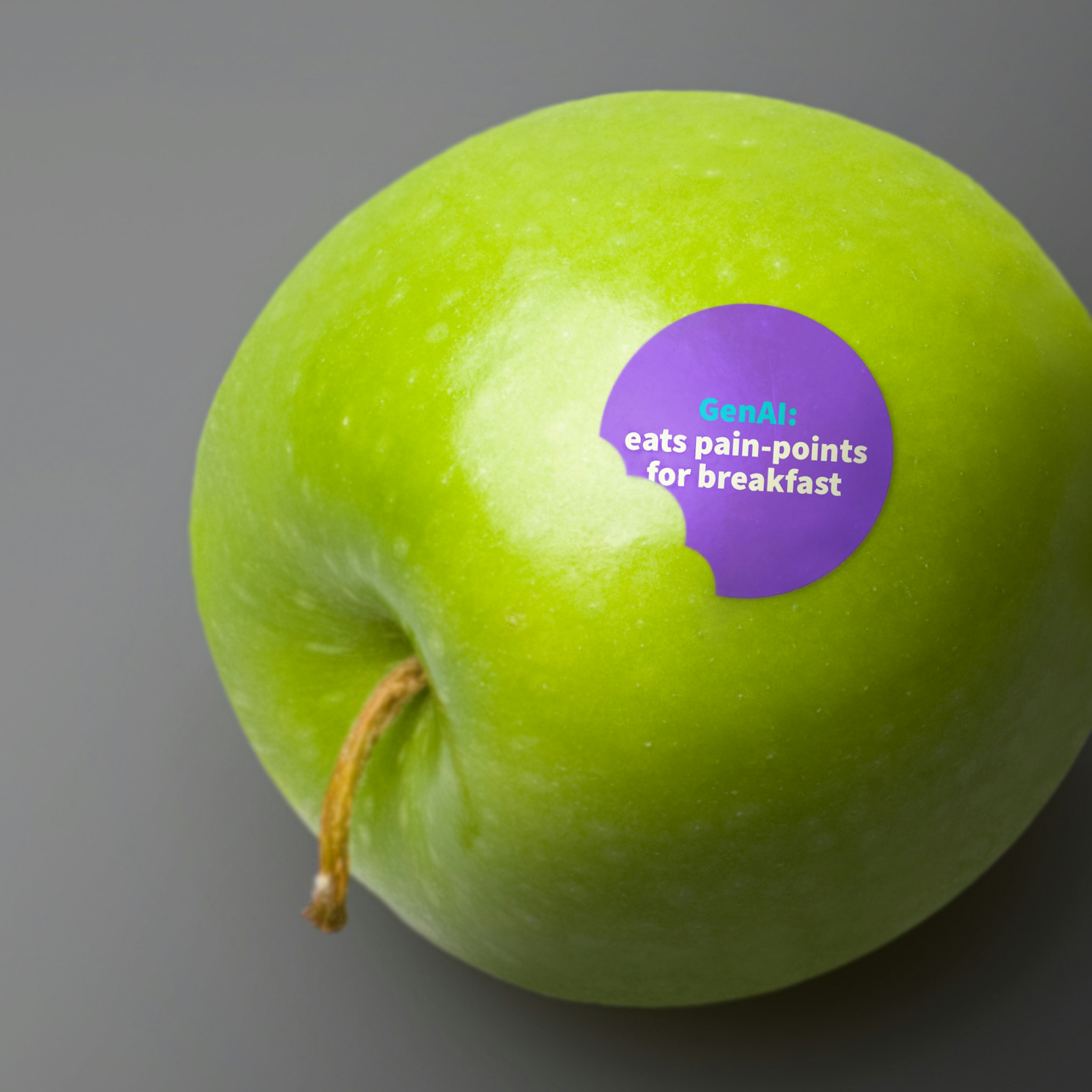Green apple on grey background with round purple sticker with message about GenAI