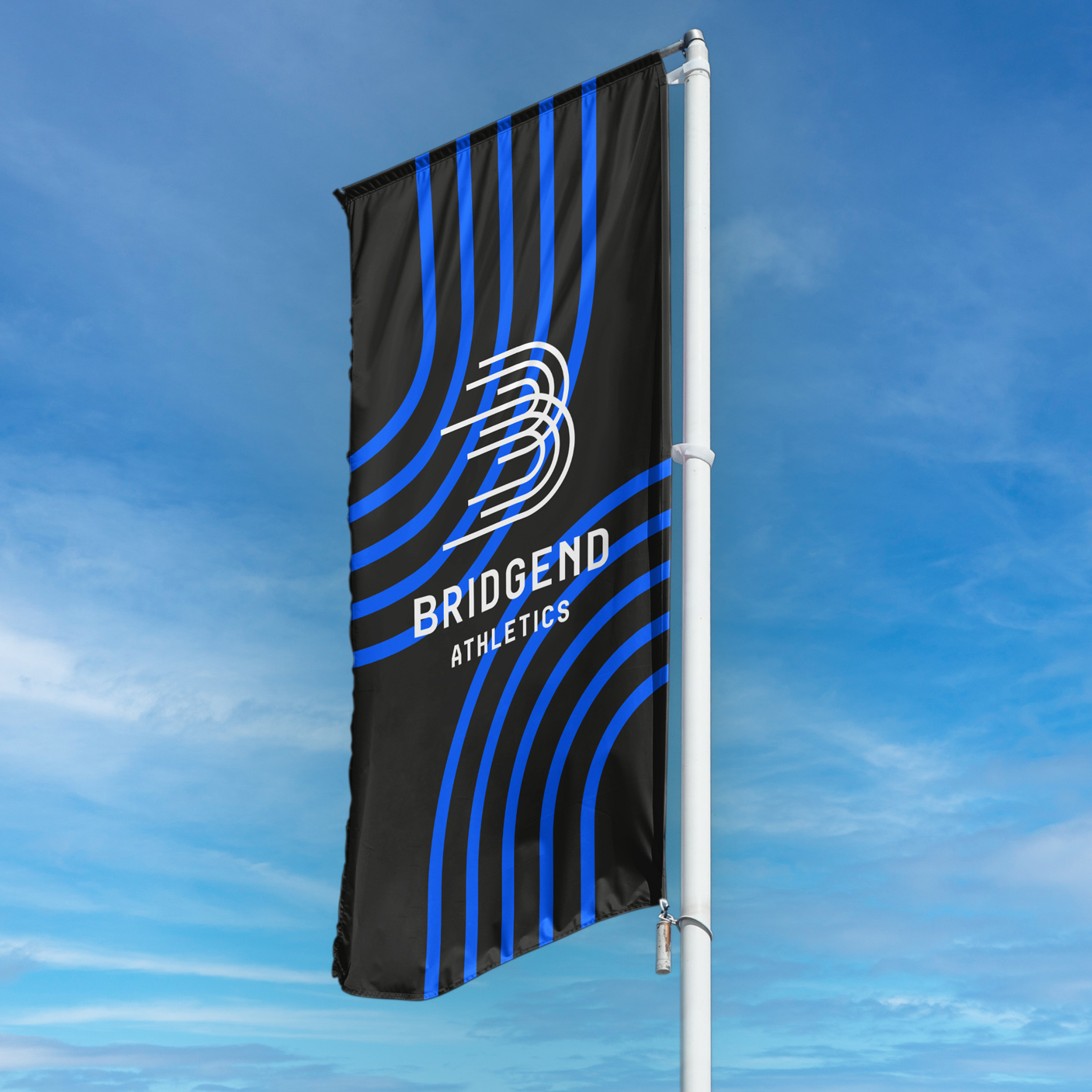Bridgend Athletics branded flag in blue, white and dark grey waving on a sunny day