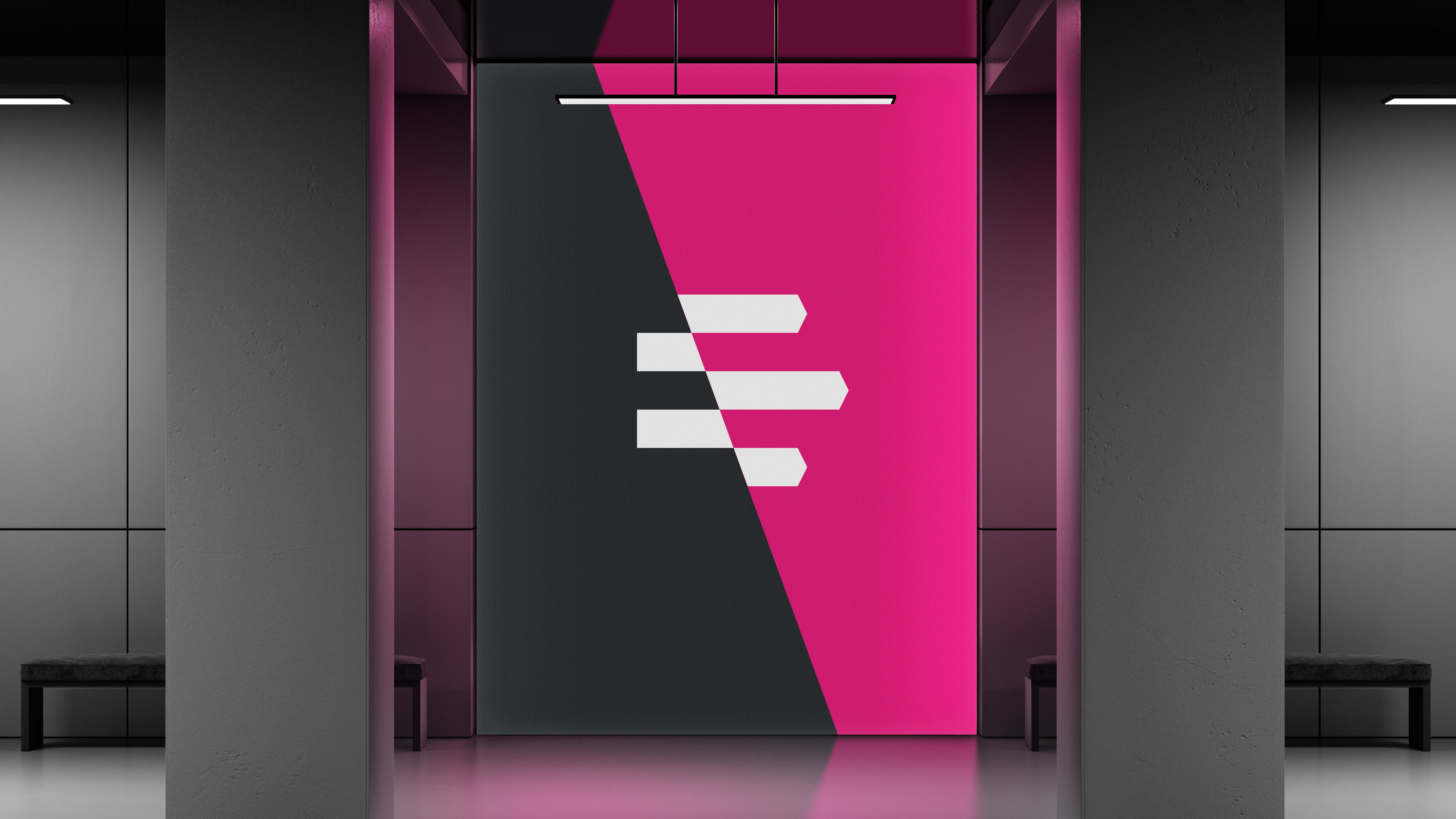 Floor to ceiling screen in modern event space showing Emergence logo mark in white on diagonally split pink and dark grey background