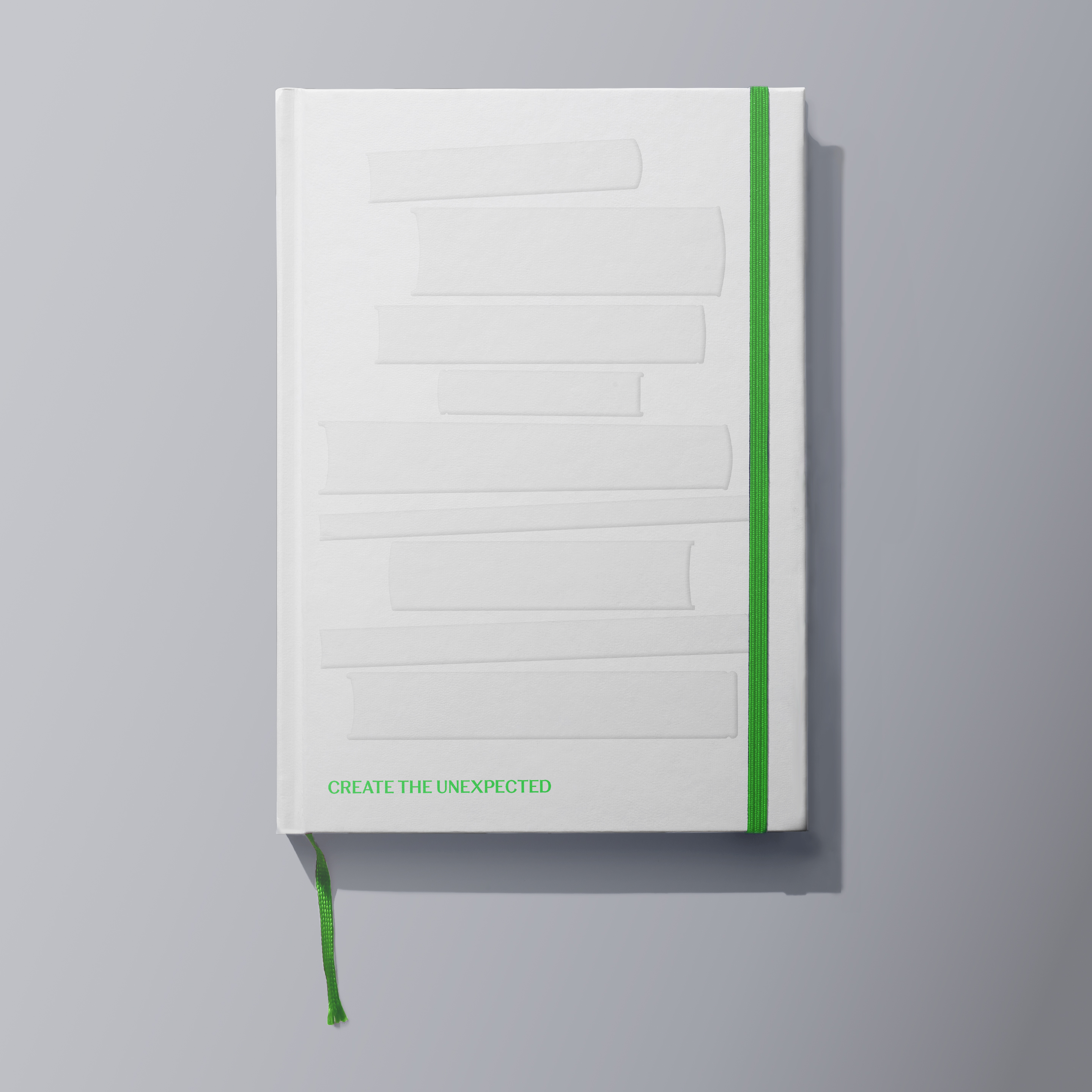 White notebook with blind embossed graphic of stacked books, 'Create the unexpected' tagline and bright green elastic band