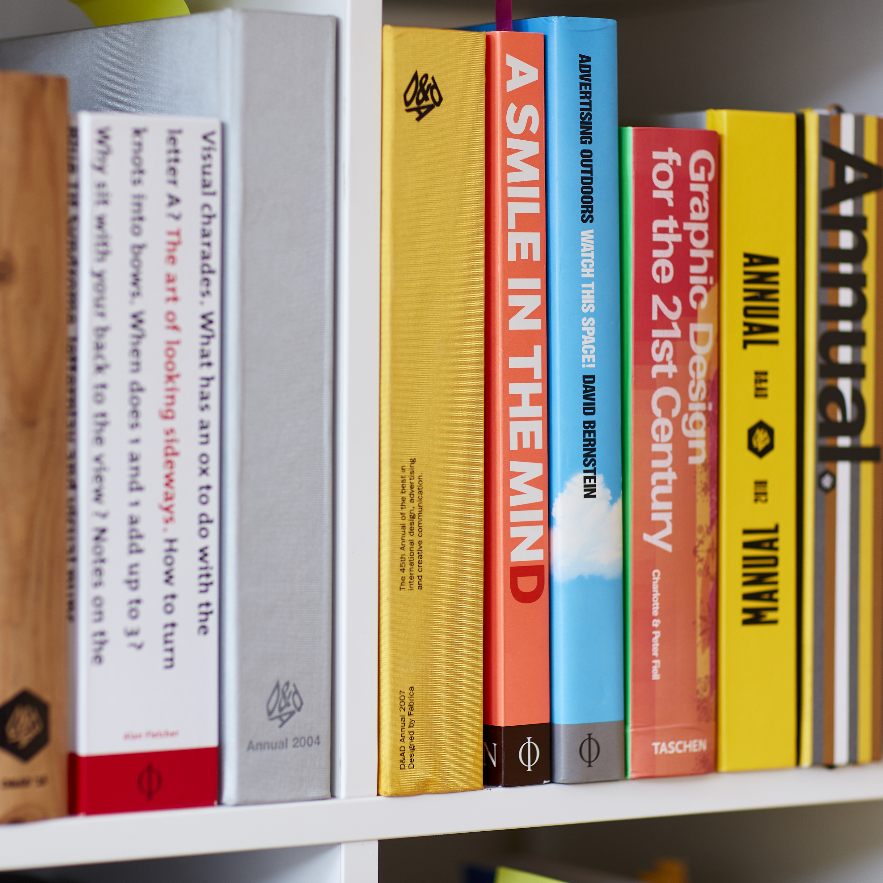 Colourful row of design and advertising books on modern design studio bookshelf