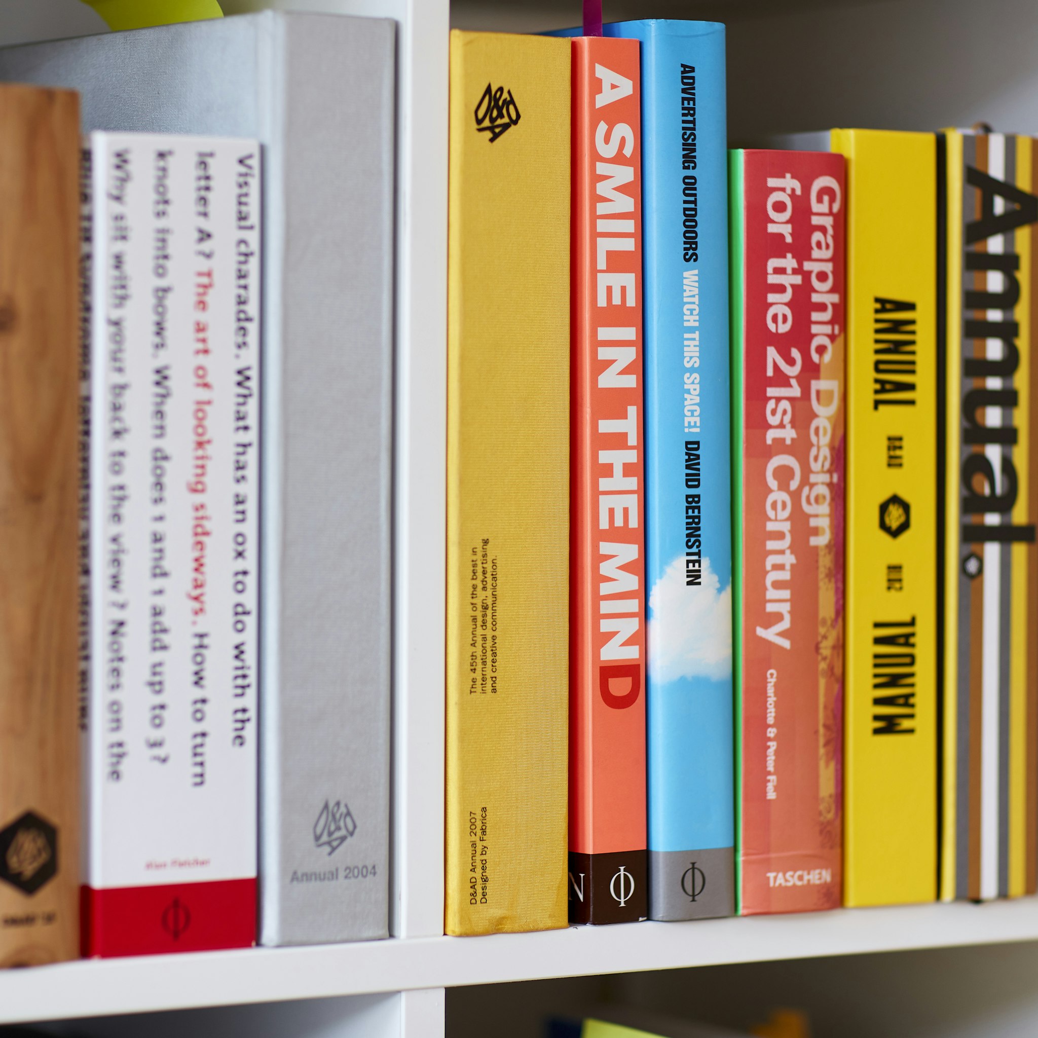 Colourful row of design and advertising books on modern design studio bookshelf