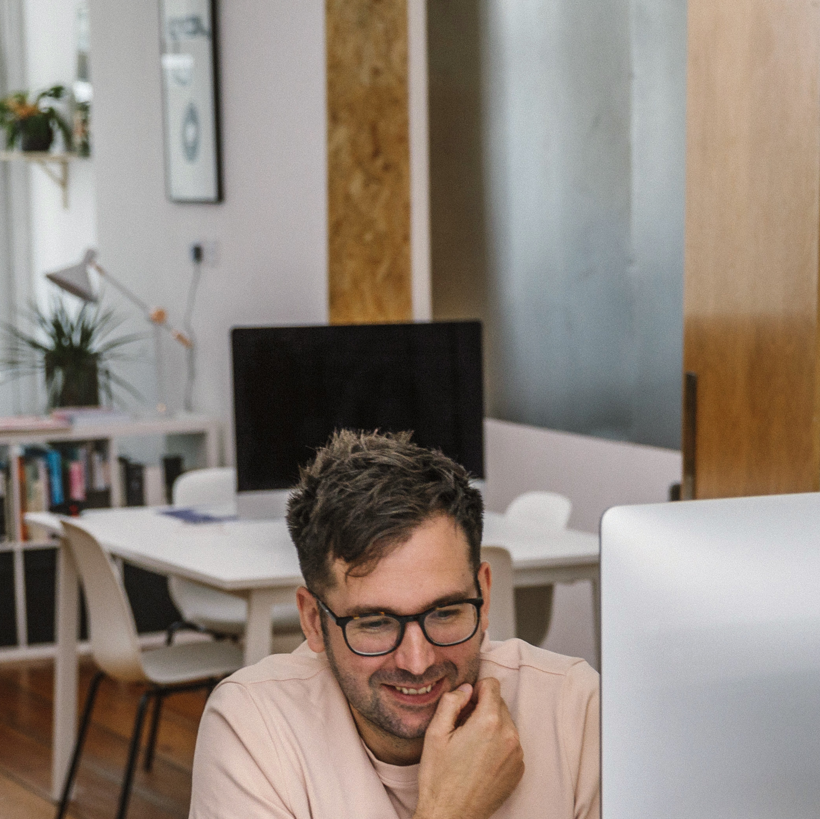 Smiling man with glasses working at computer in creative modern design studio