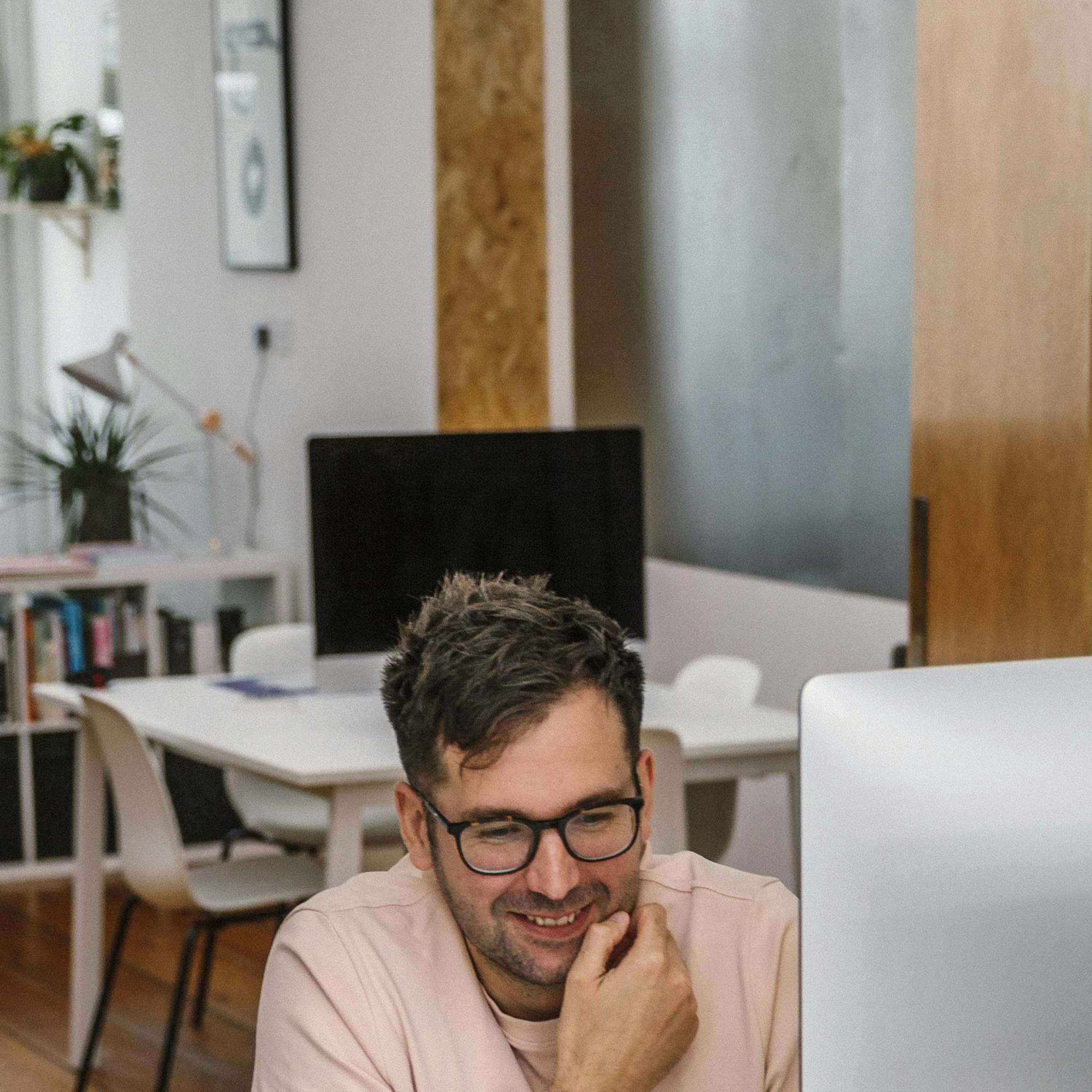 Smiling man with glasses working at computer in creative modern design studio