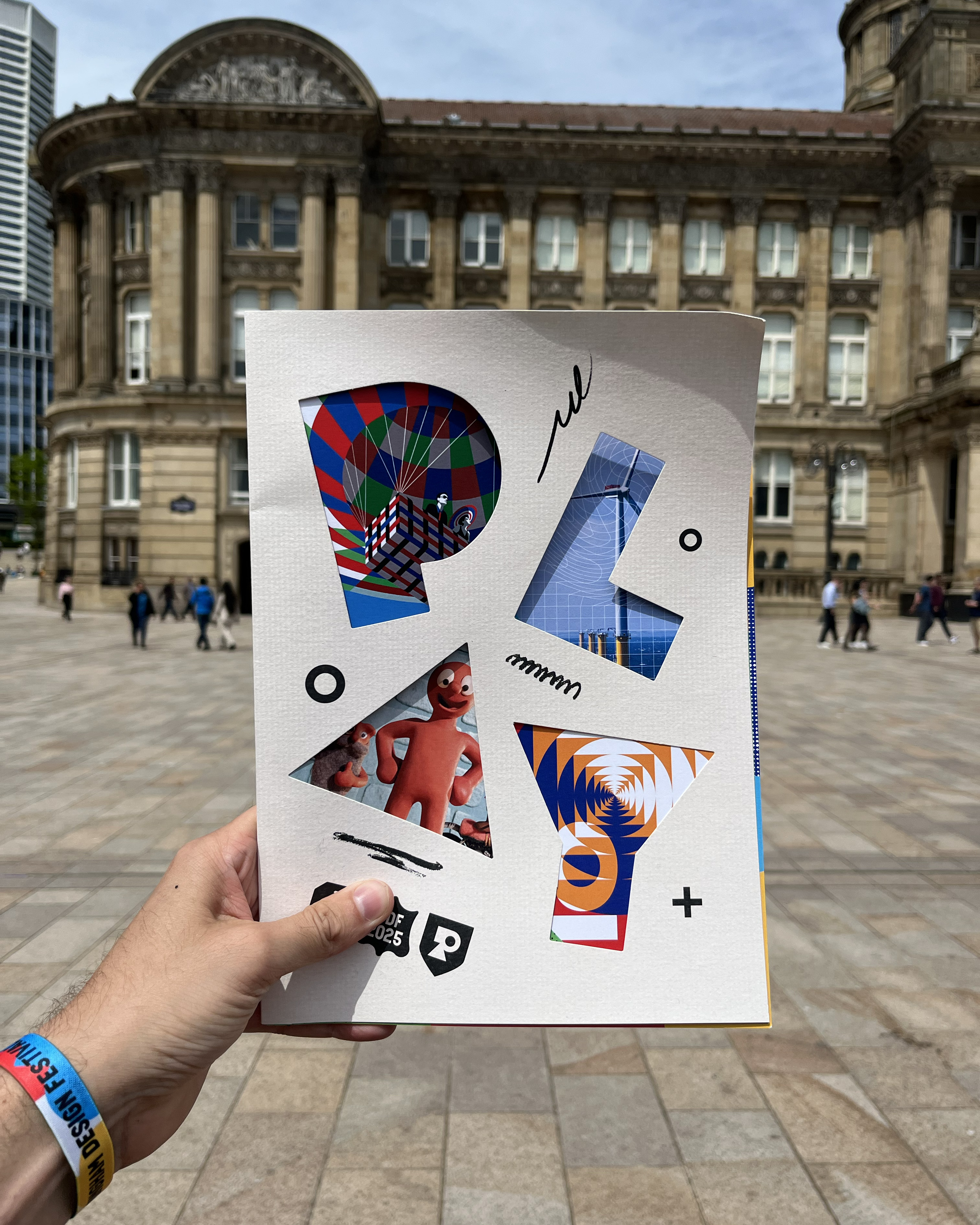 Attendee holding Birmingham Design Festival 2025 brochure outside the venue, highlighting event participation and design focus