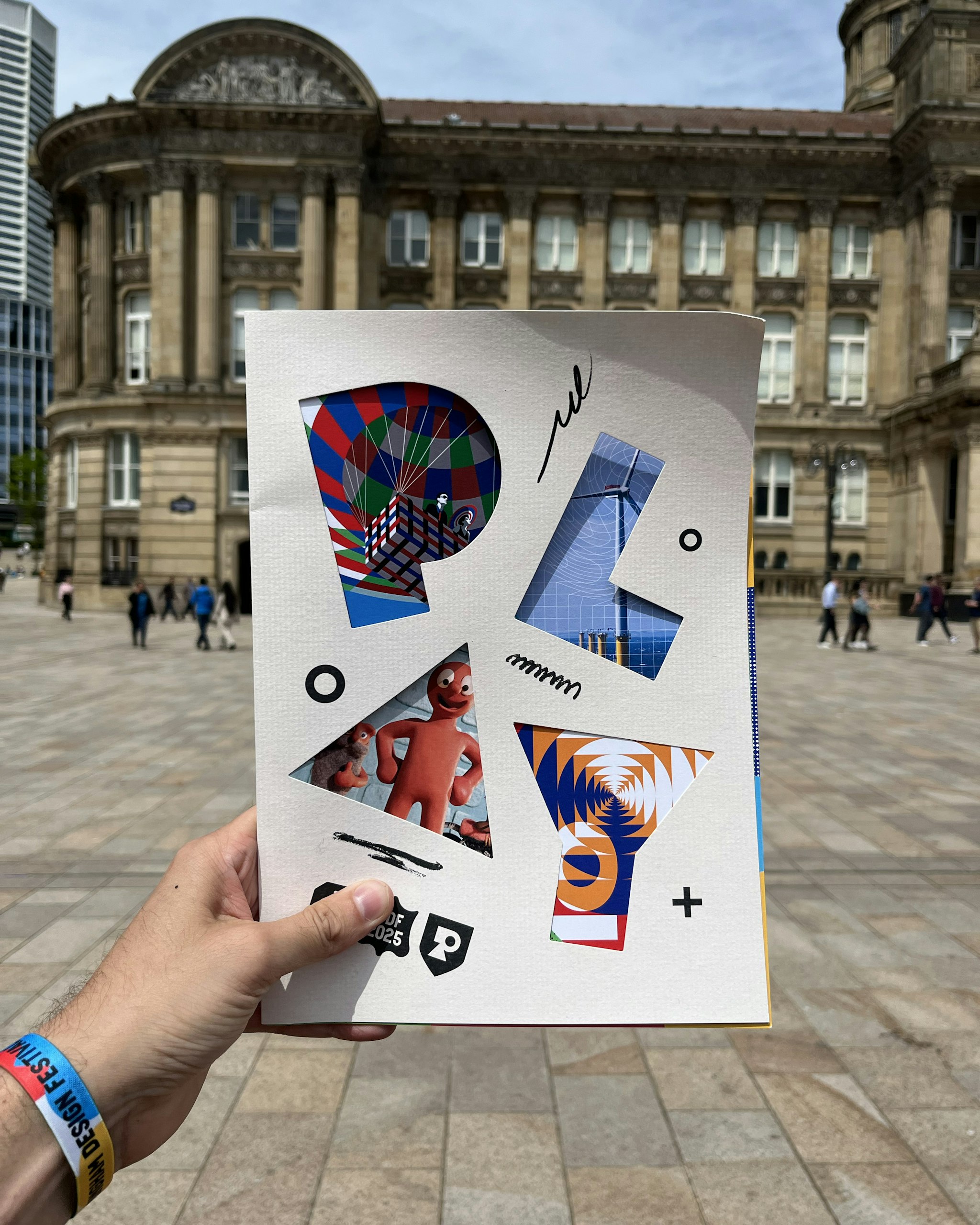 Attendee holding Birmingham Design Festival 2025 brochure outside the venue, highlighting event participation and design focus