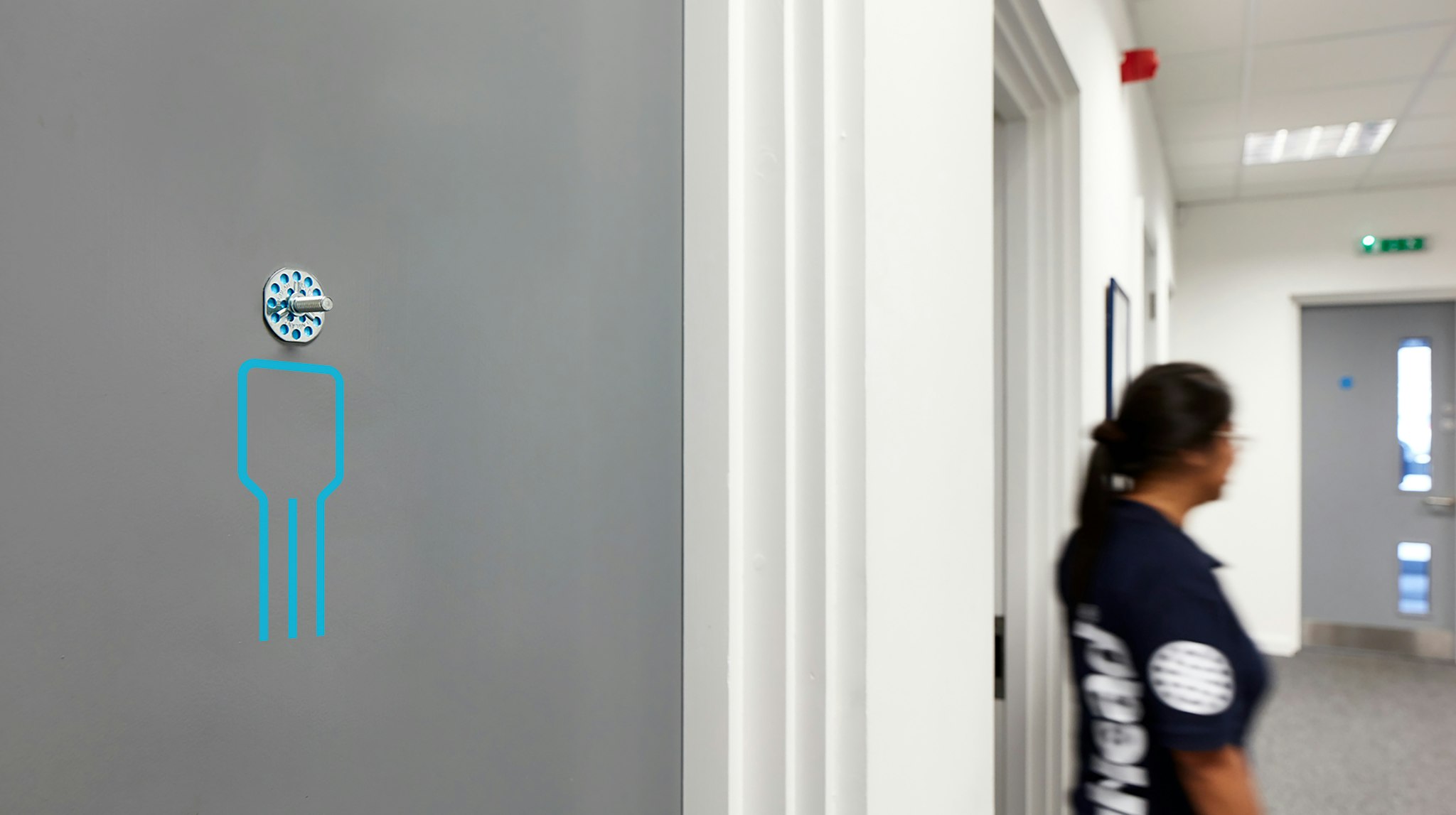 Men’s toilet sign using bigHead screw as head with woman in company shirt walking past