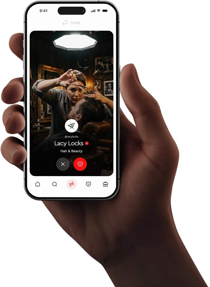A hand holding an iPhone with the Pocketchange mobile app open, featuring a barber mid-haircut in a cosy, vintage barbershop. The screen shows the Lacy Locks Hair & Beauty profile, highlighting local businesses inside the Pocketchange platform.